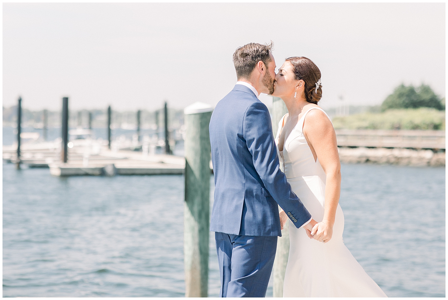 candid picture of bride + groom kissing on boat dock