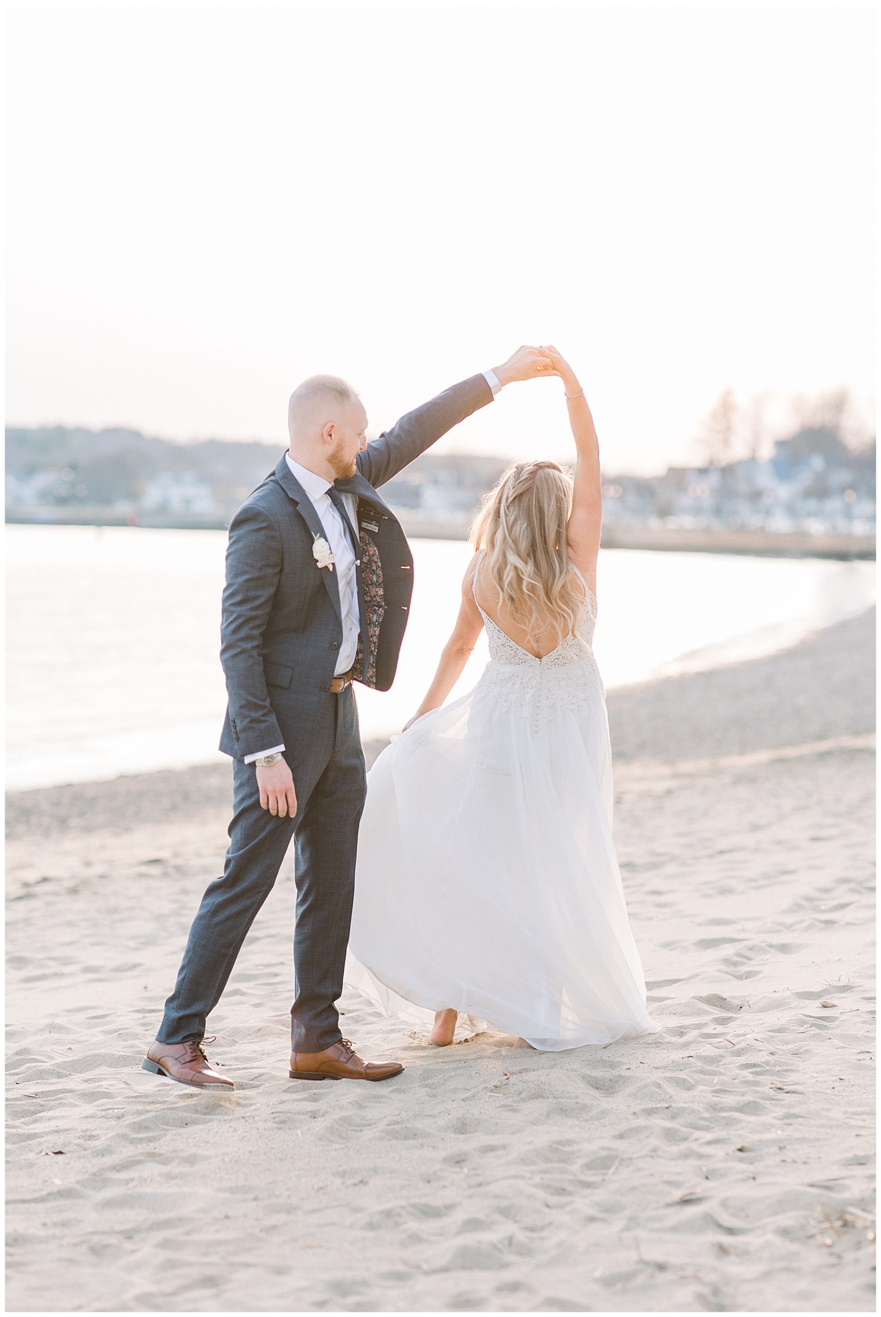 groom twirls bride during photos on beach