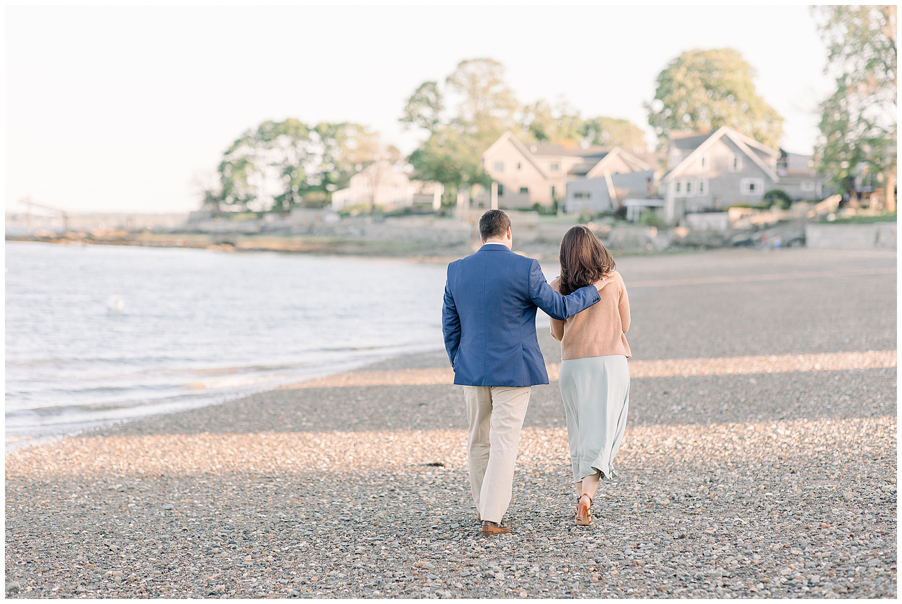 couple walks along shoreline in Boston MA