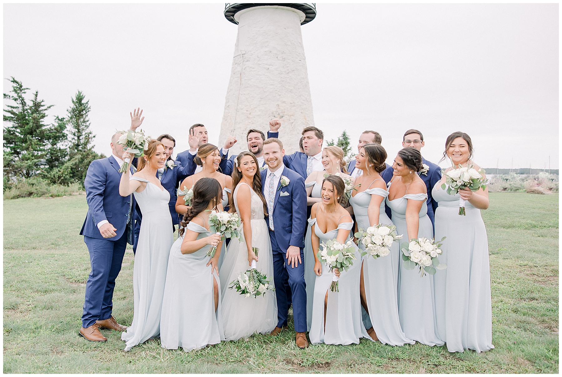 bride and groom with bridal party in front of MA lighthouse