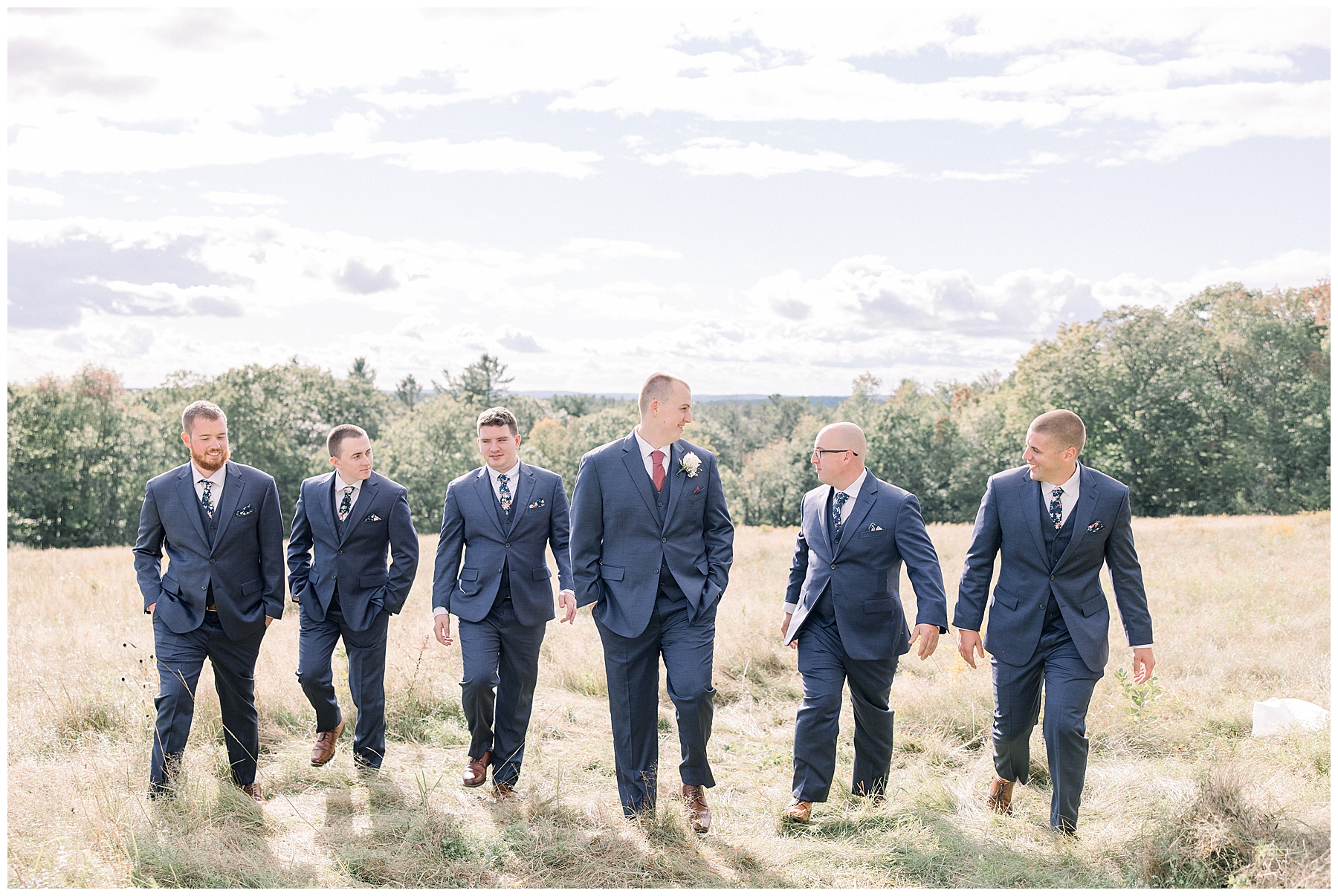 groom and groomsmen walking in field on the grounds of  Harrington Farm in Princeton MA
