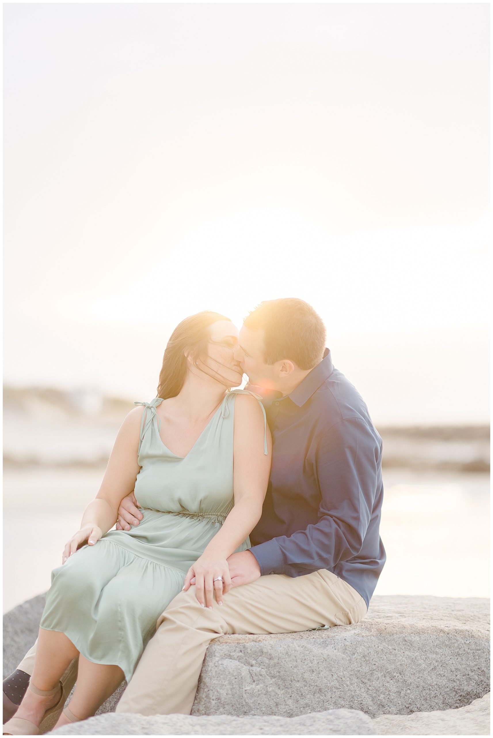 couple kiss as the sun shines behind them 