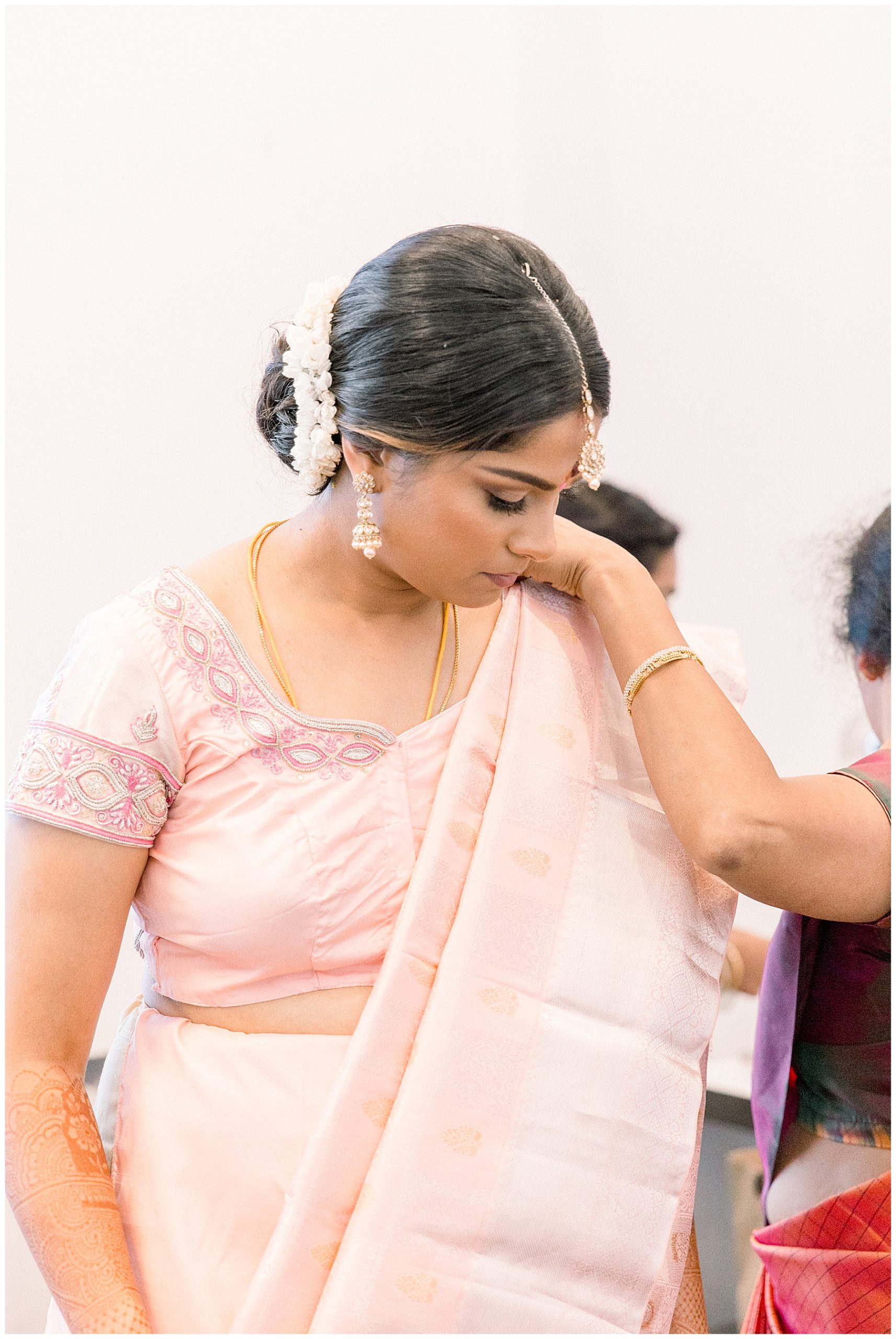 bride getting ready in light pink indian outfit