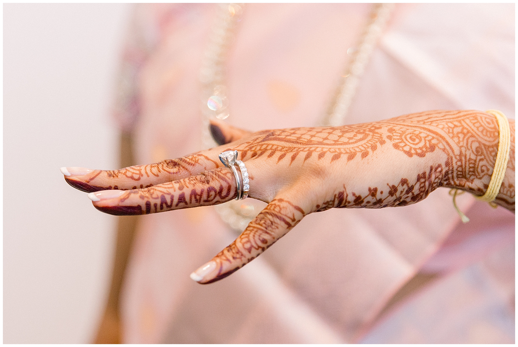 bride shows off wedding ring and henna art
