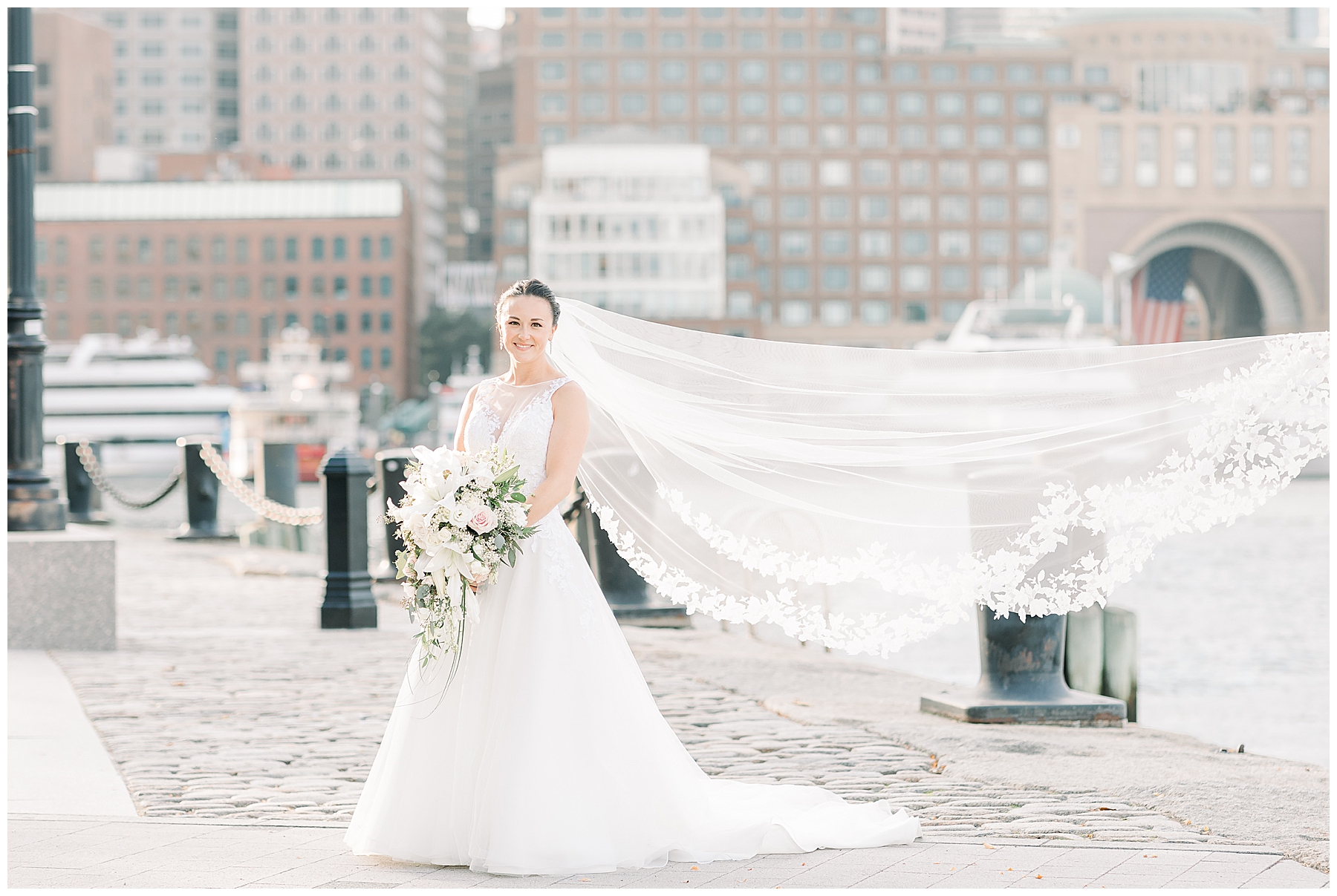bride stands at Fan Pier in Boston with veil blowing behind her