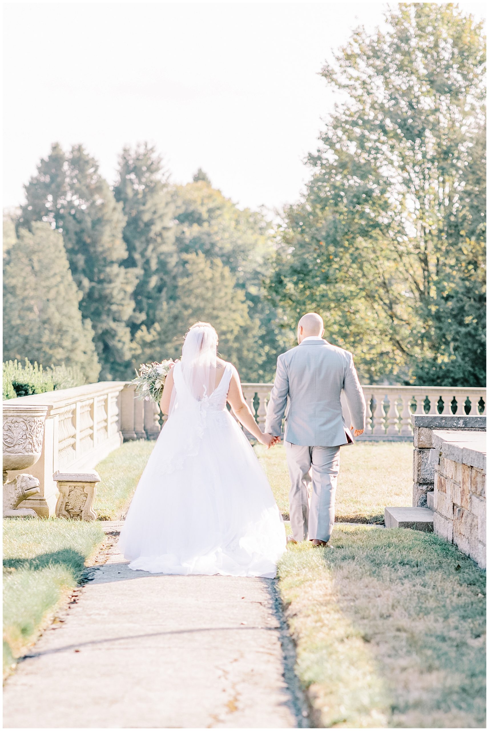 newlyweds hold hands and walk through the grounds of mansion