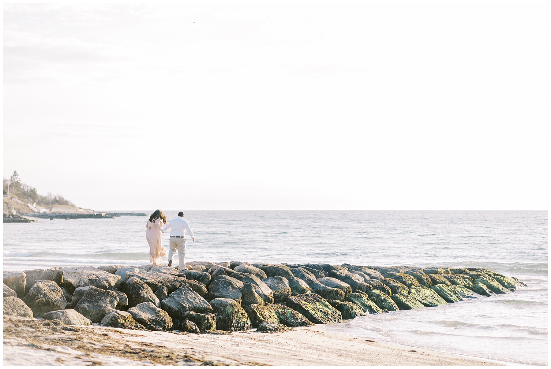 couple walk out on rocks on the beach during Engagement Session

