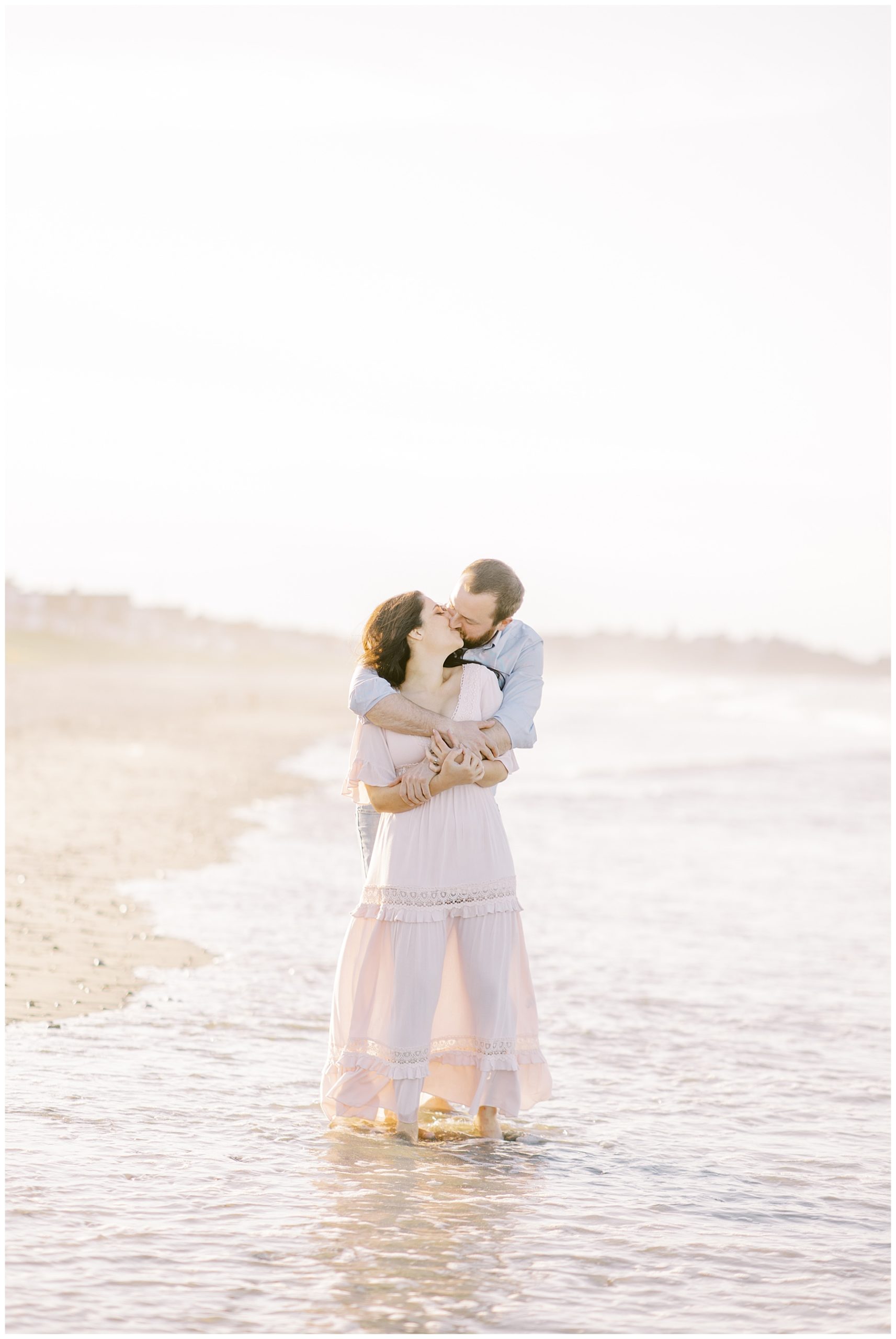 couple stand in the ocean water and kiss 