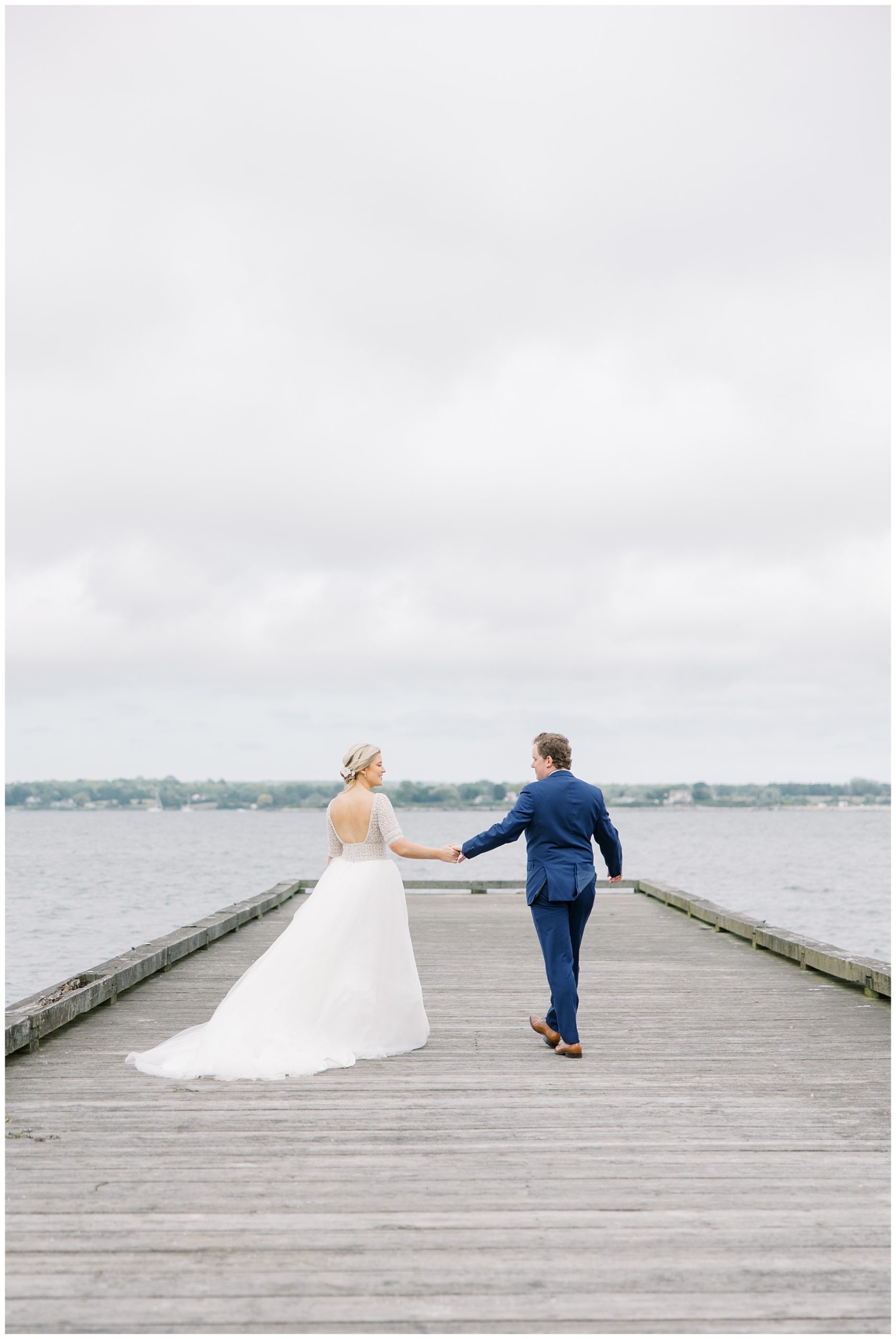 bride and groom walk out on the dock 