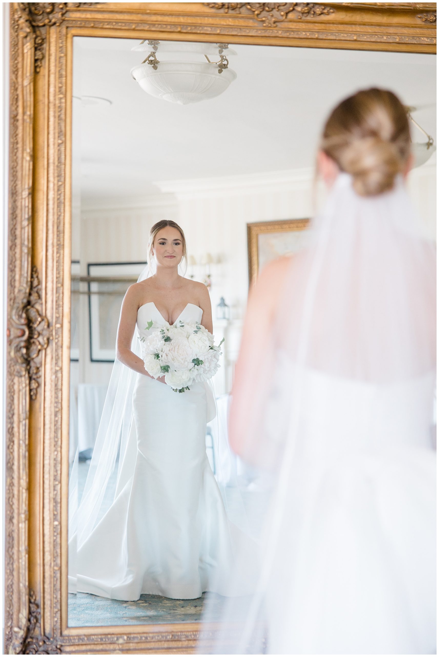 bride looking in gold framed mirror 