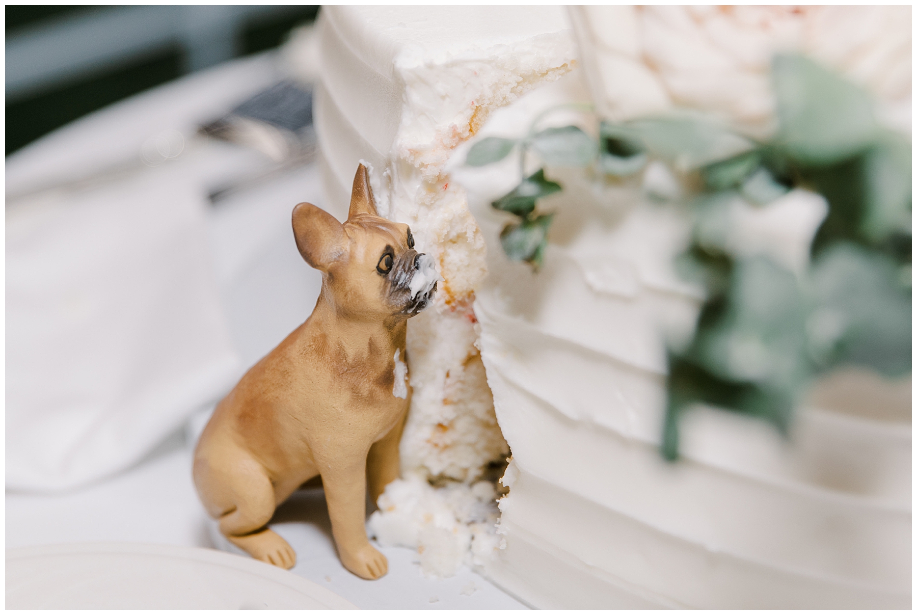 wedding detail of dog figurine on cake made to look like he was eating it 