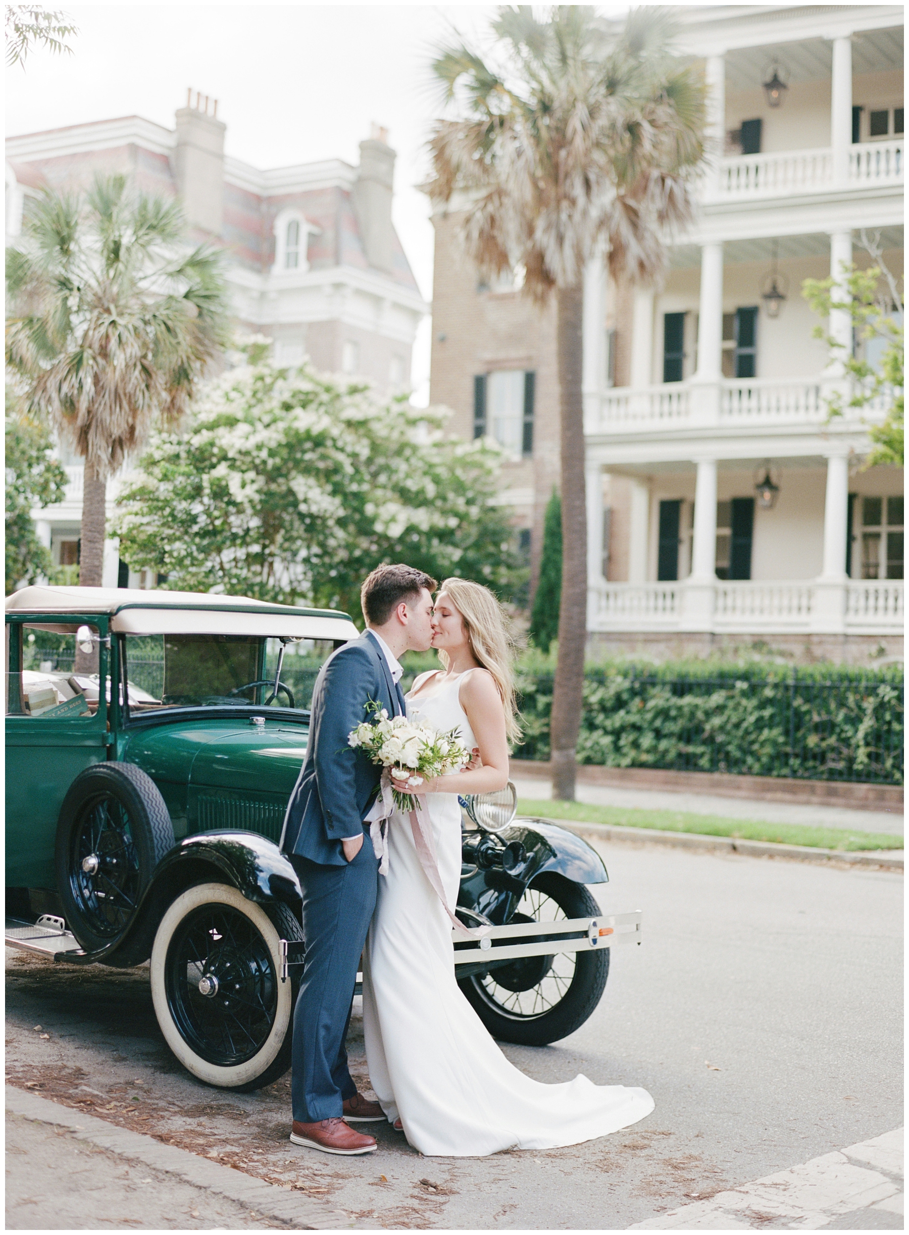 newlyweds kiss in front of green car 