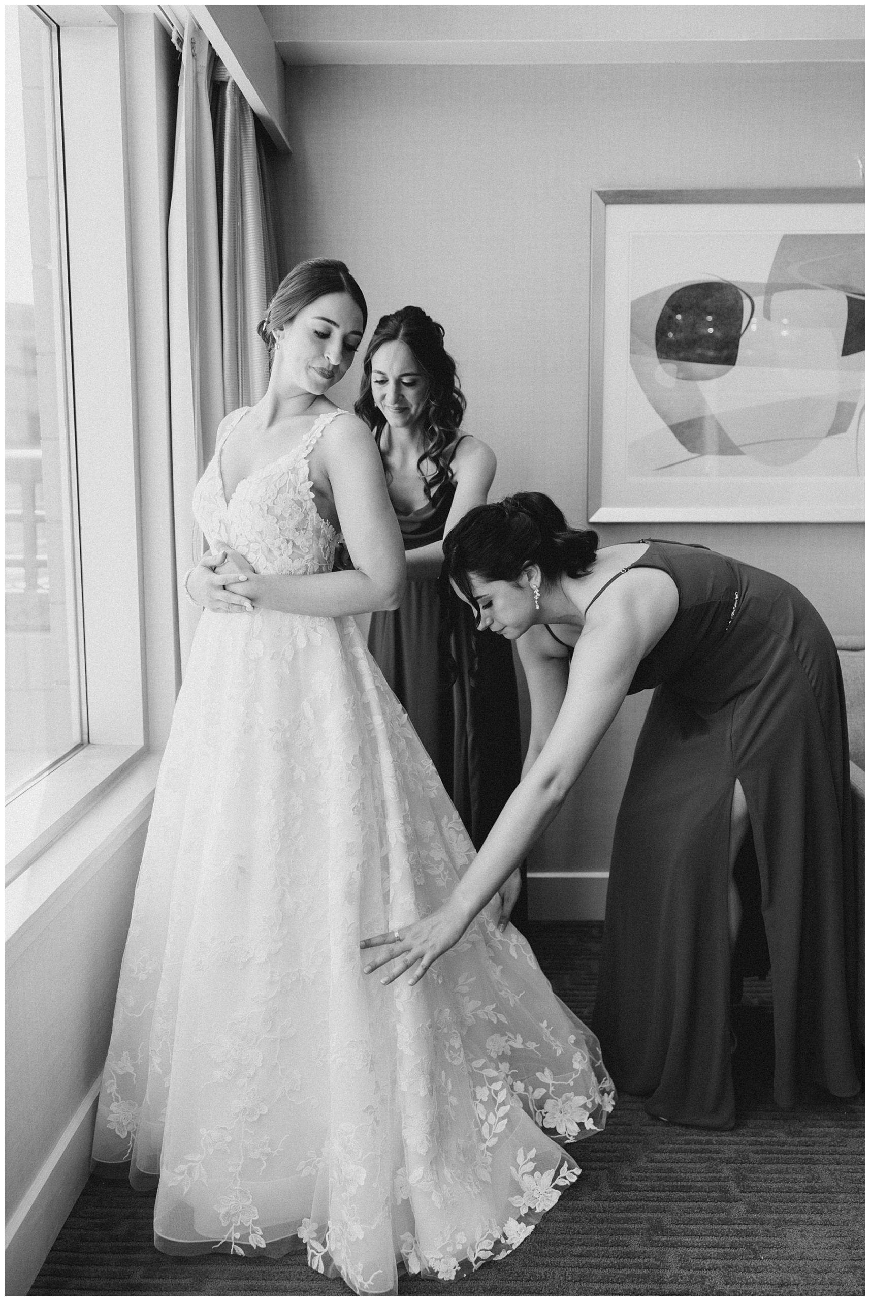 bride getting into her wedding dress with bridesmaids