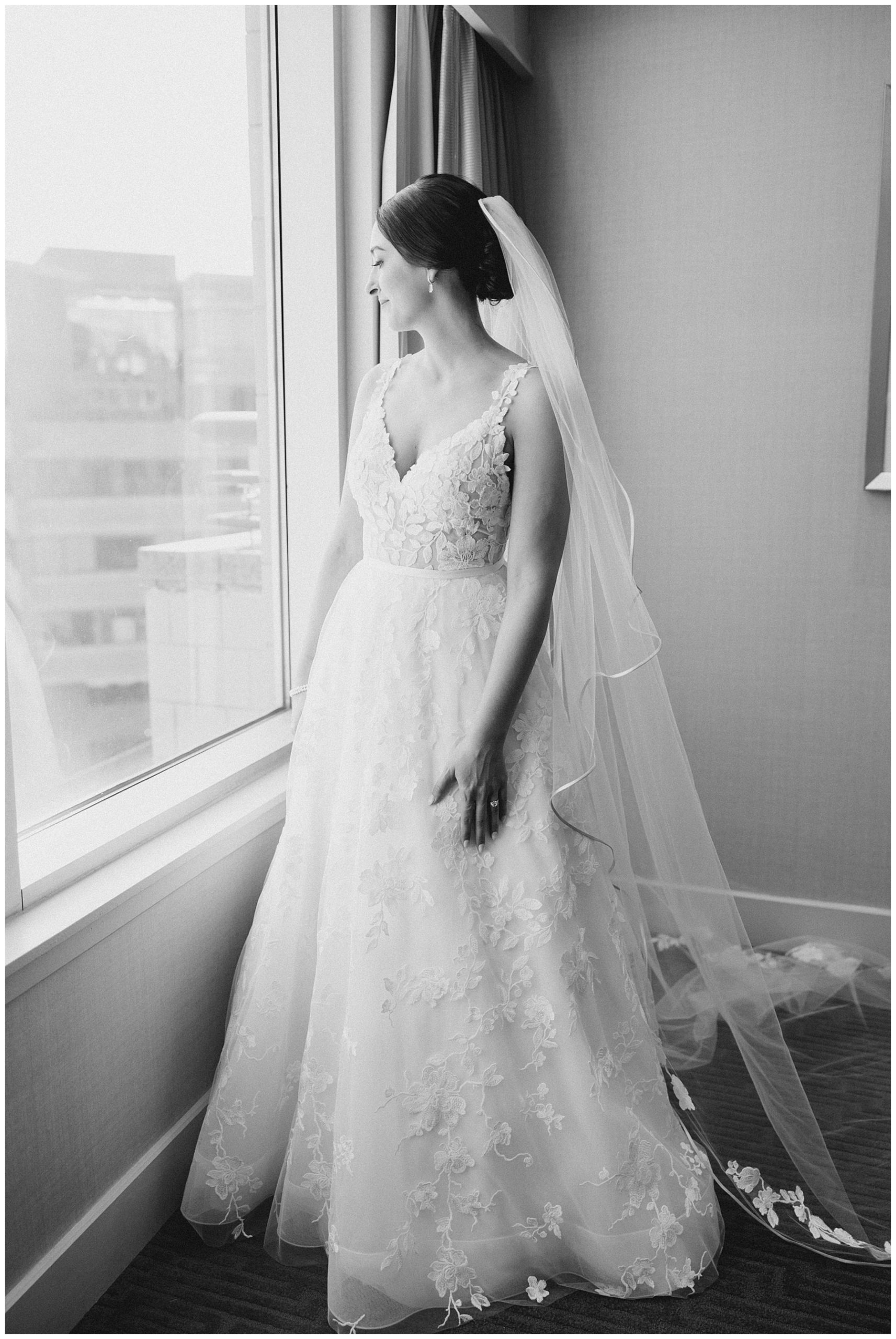 bride in wedding dress looks out of window from suite 