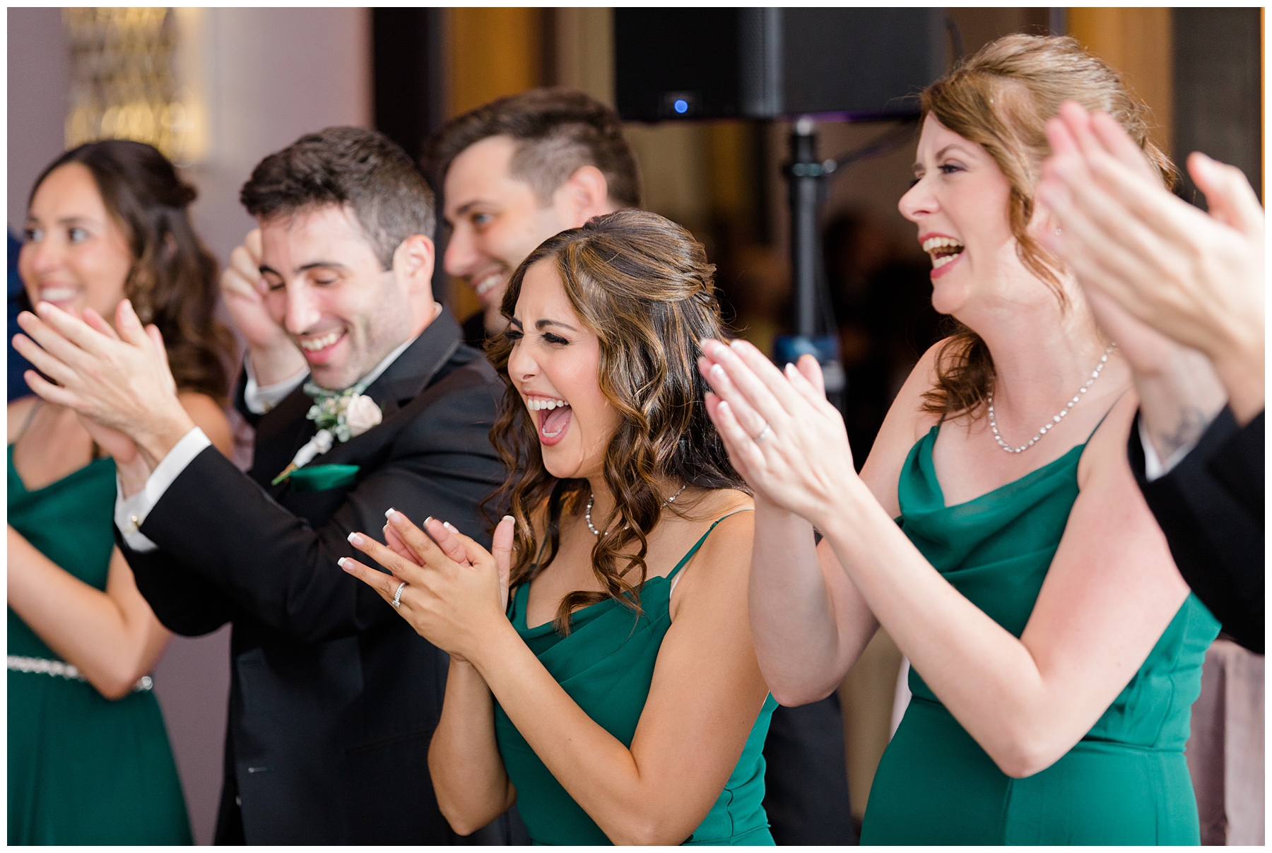 bridal party laughing and cheering bride and groom at reception