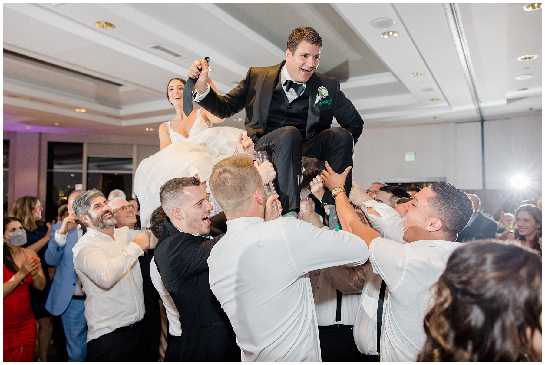 bride and groom lifted up during traditional greek dance