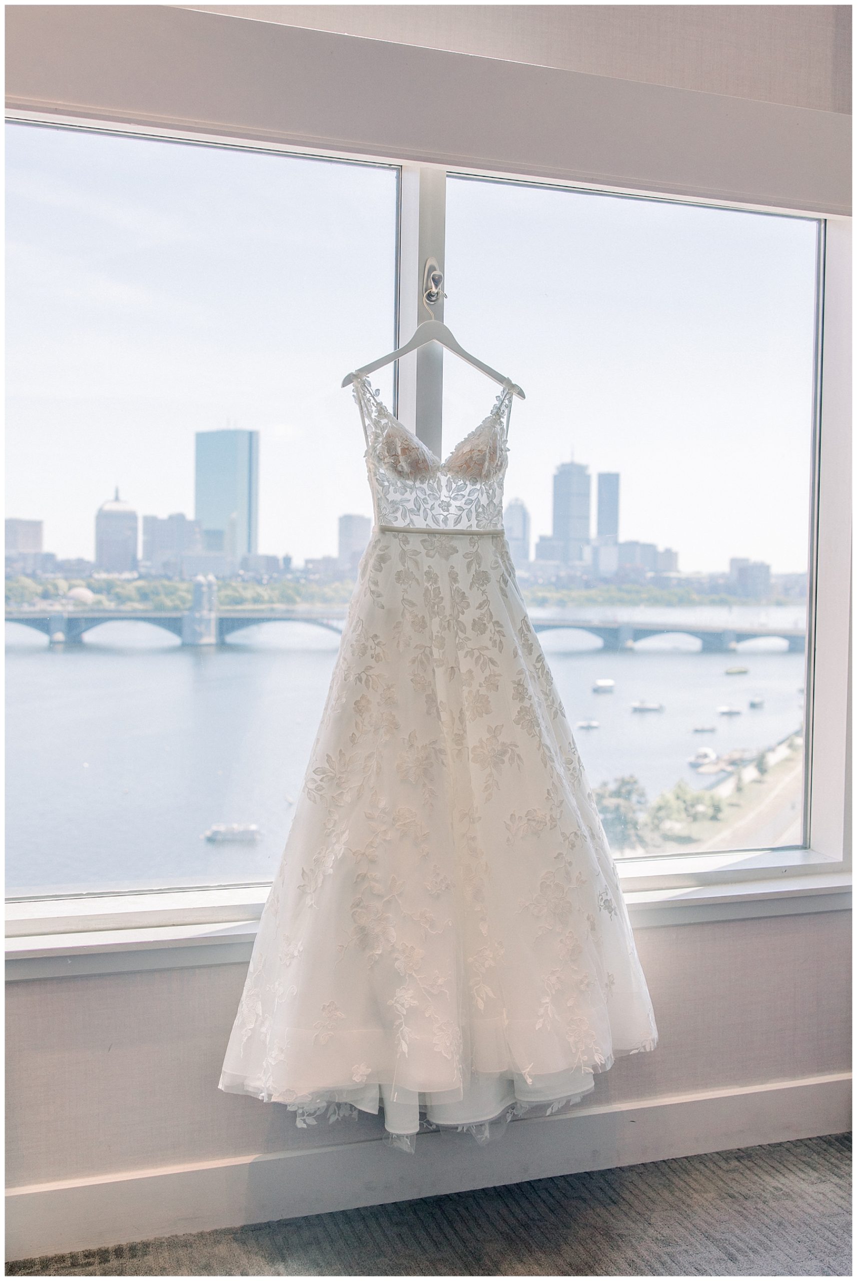 wedding dress hanging by window featuring Boston skyline