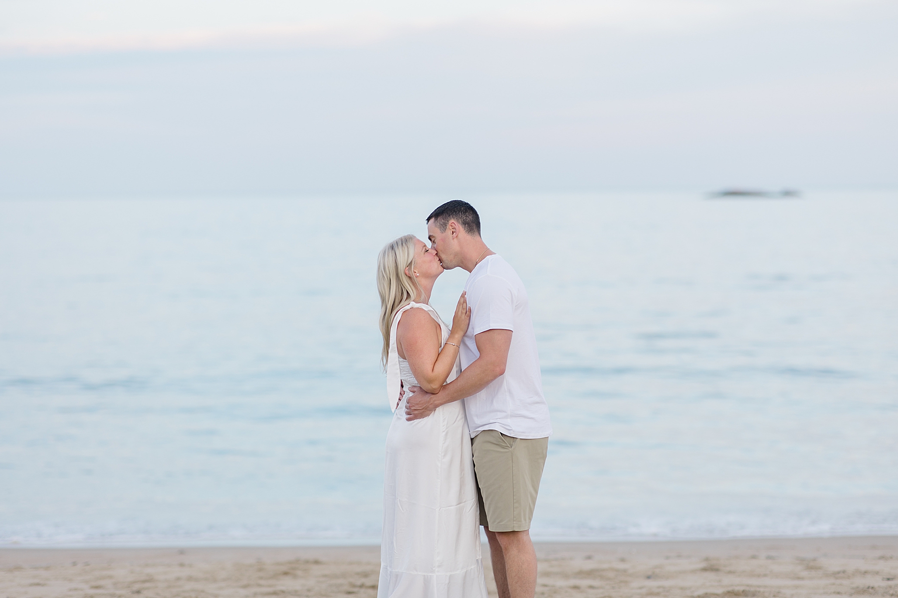 couple kiss on the beach in MA during engagement portraits 