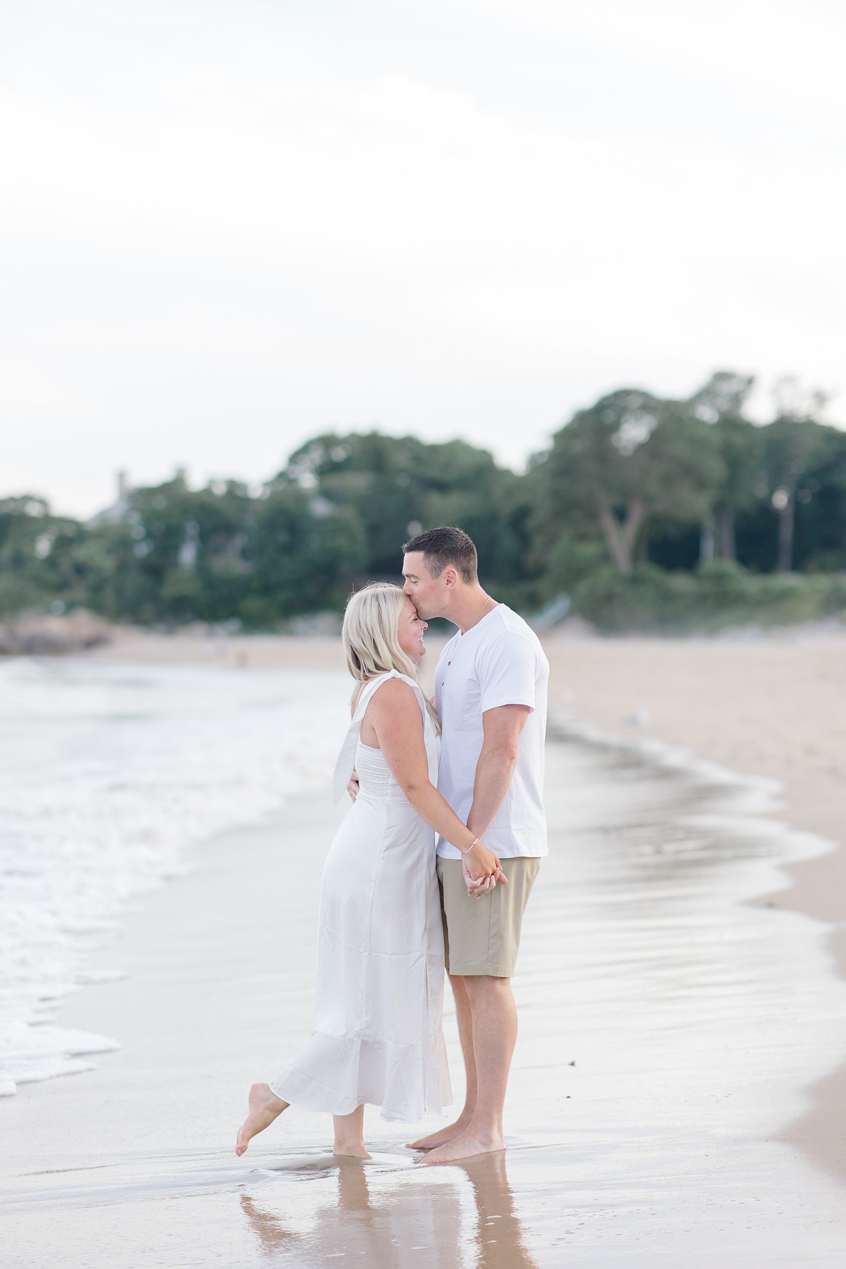 man kisses his fiancé's head during Timeless Beach Engagement | Boston Engagement Photographer