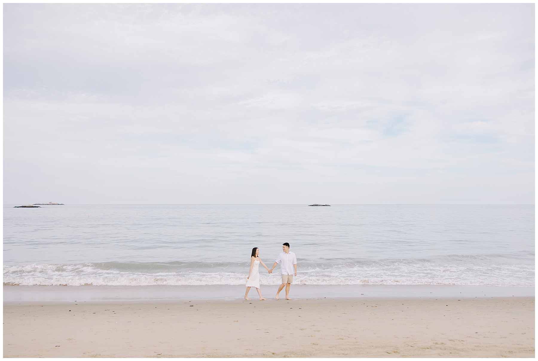 engaged couple walk along the beach