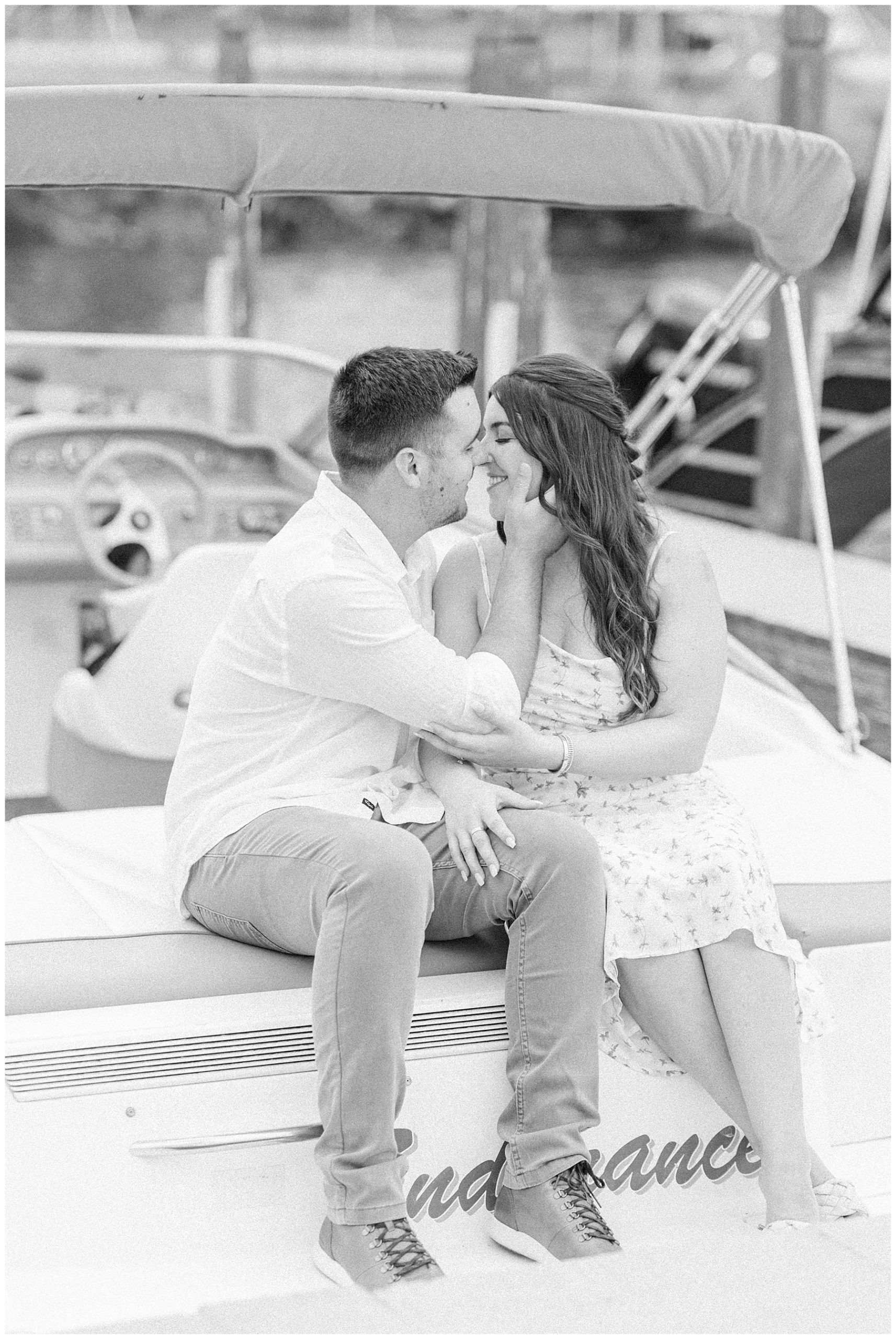 newly engaged couple sit on their boat for engagement portraits 
