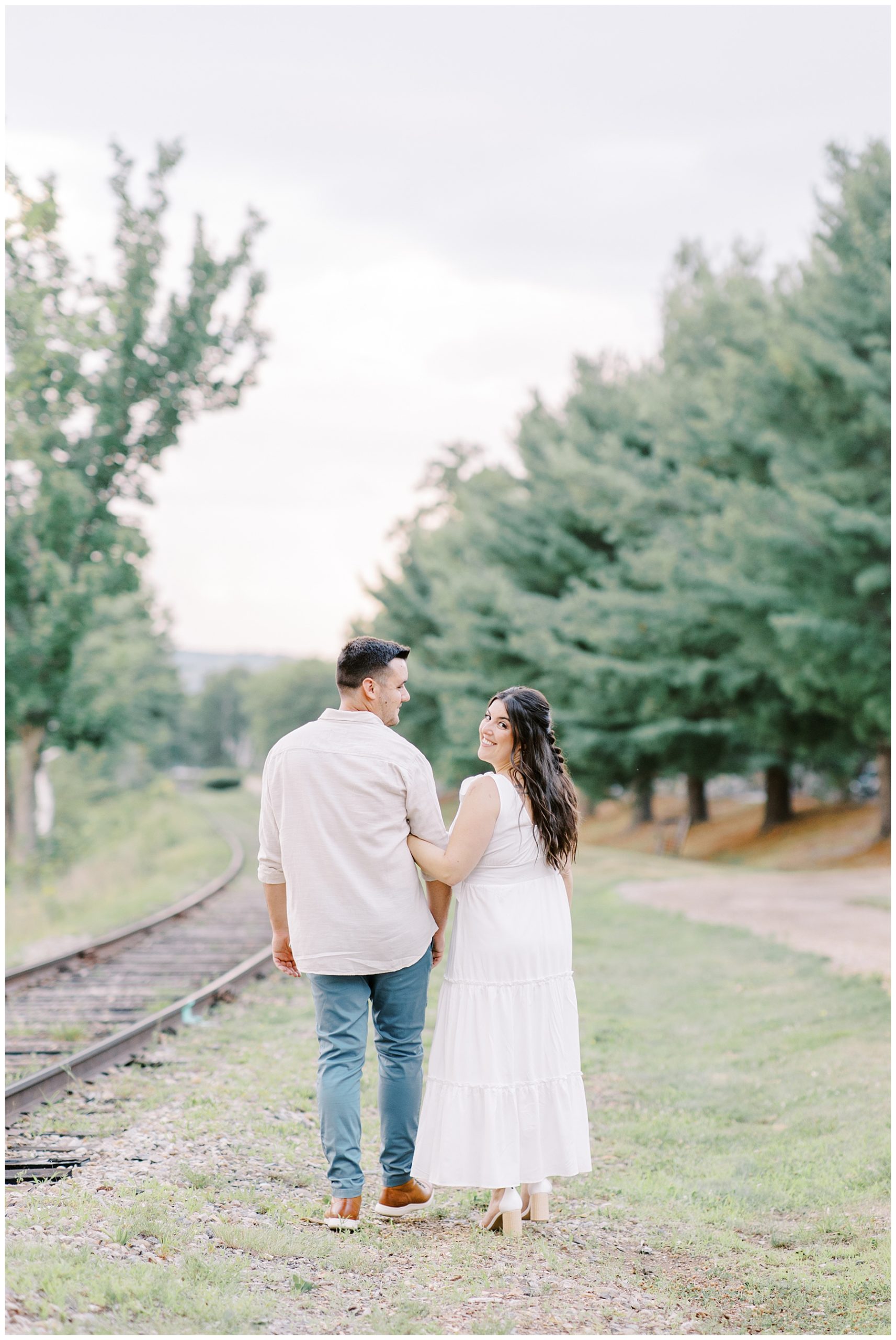 couple walk together next to railroad tracks