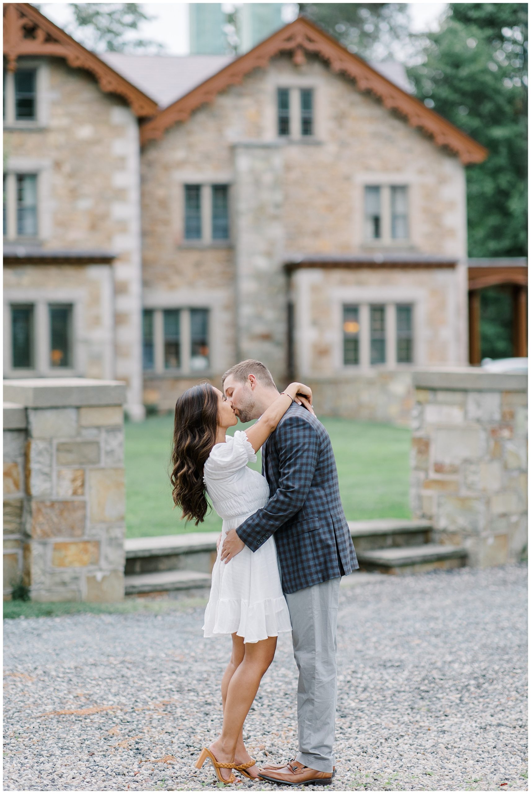 couple kiss in front of Boston estate during engagement session