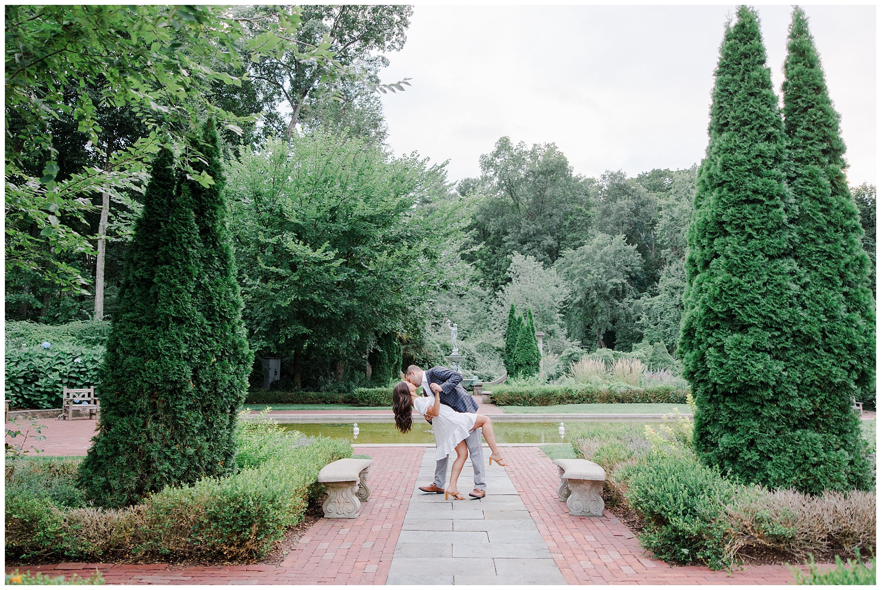 man dips his fiance in the garden during engagement portraits