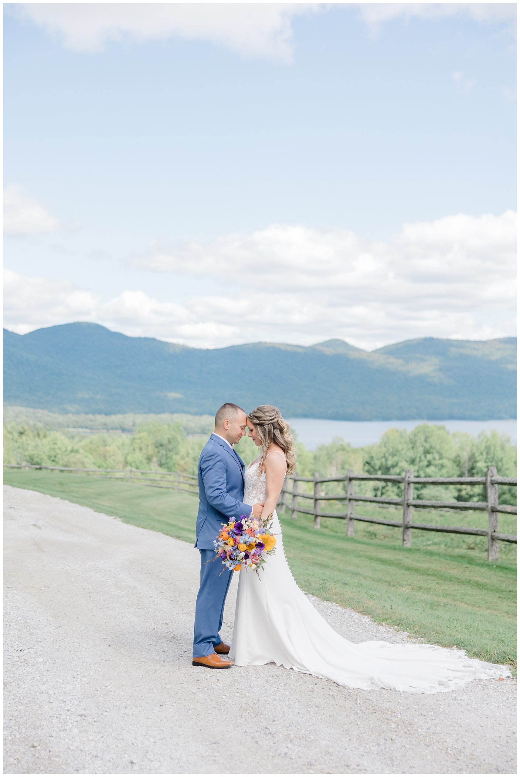 couple lean in together during wedding portraits with the Vermont green mountains in the background