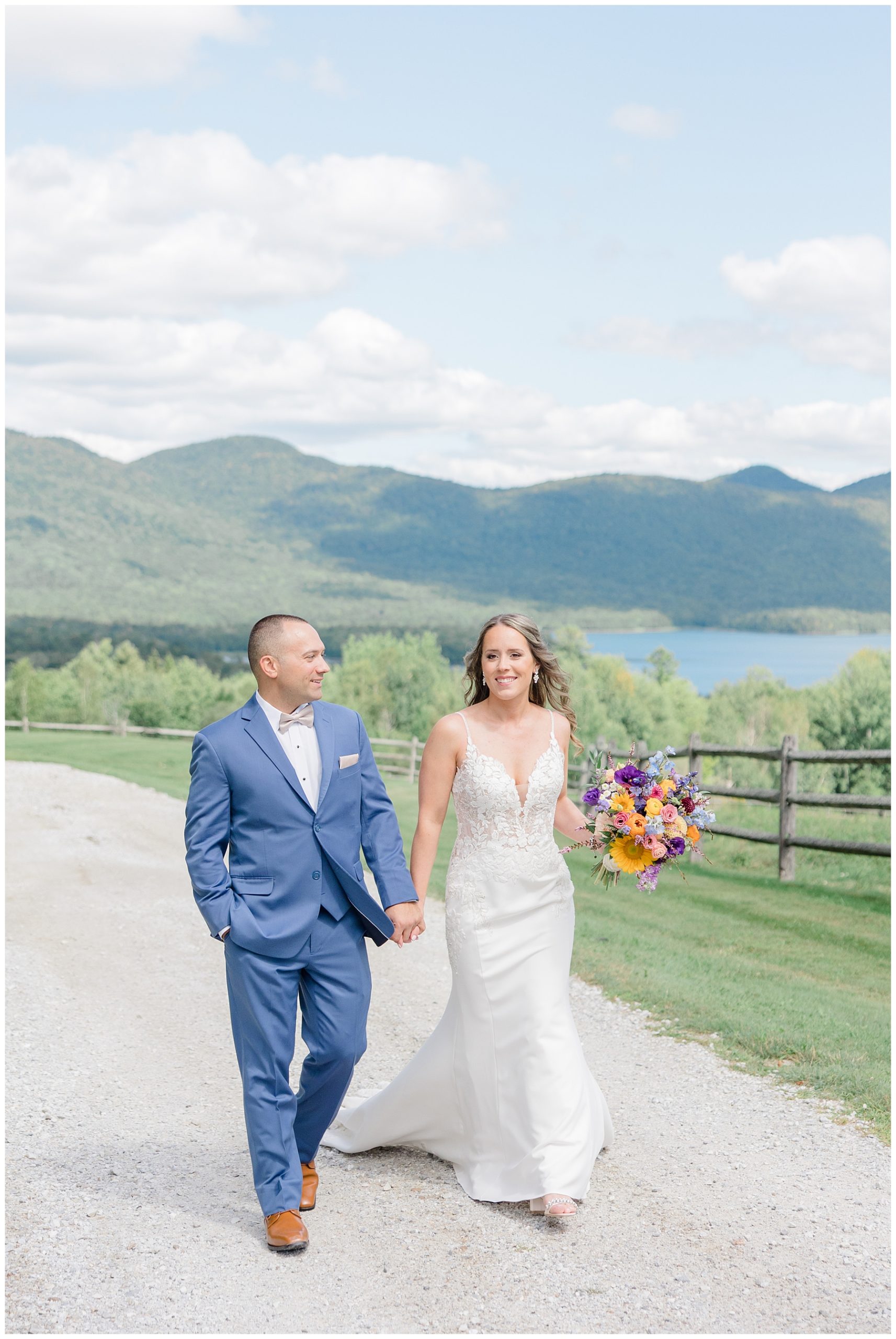 bride and groom walking along gravel road near green mountains in Vermont