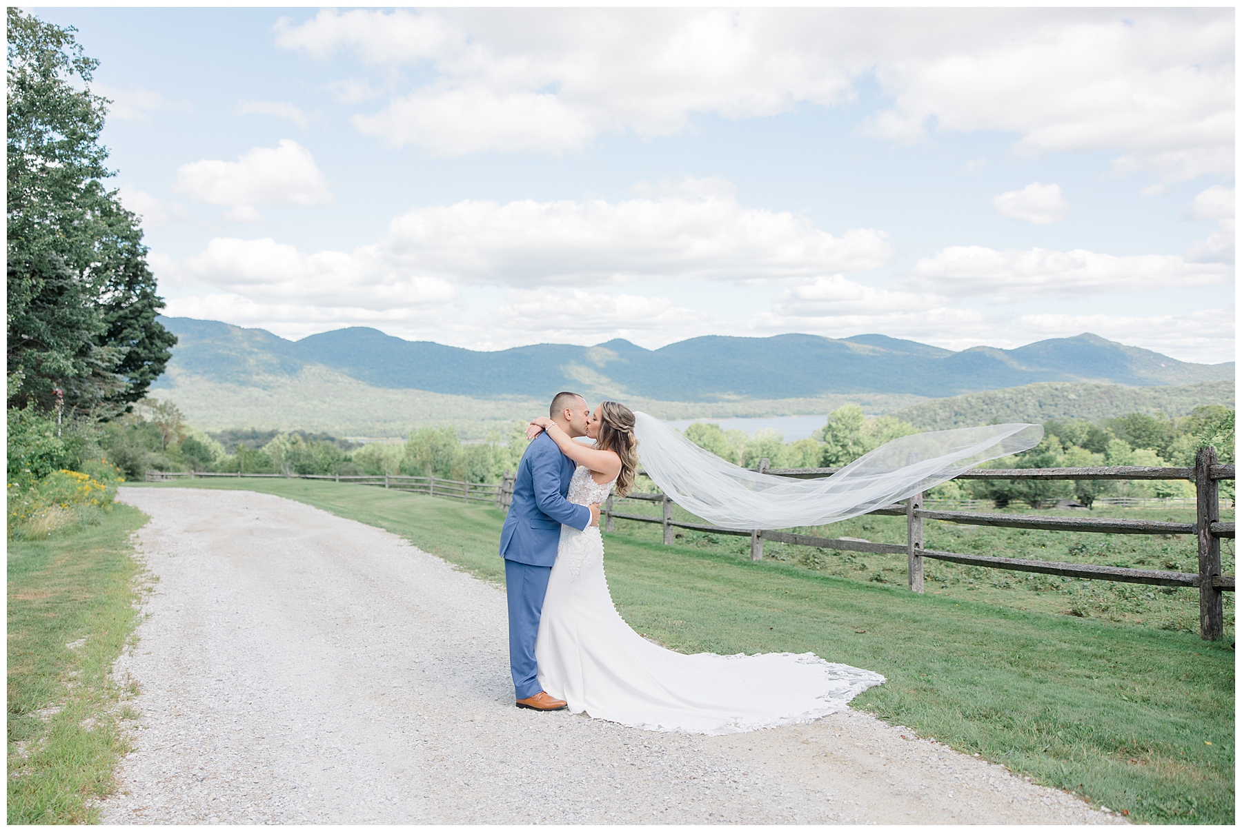 couple kiss near mountains as bride's veil flows behind them 