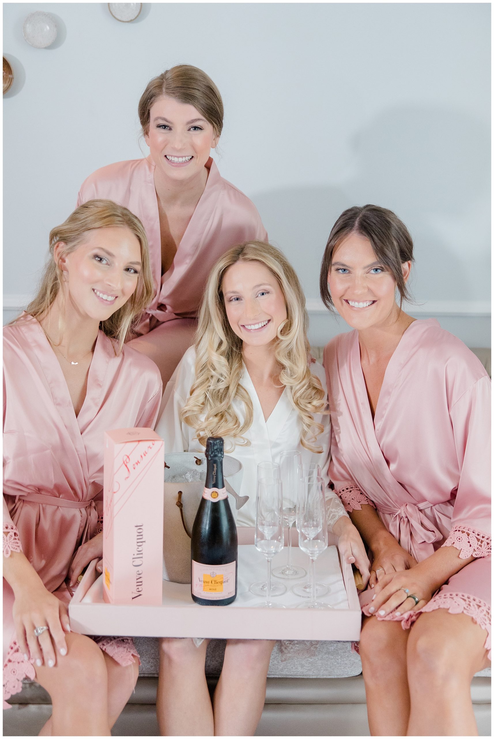 bride sits with bridesmaids holding champagne 
