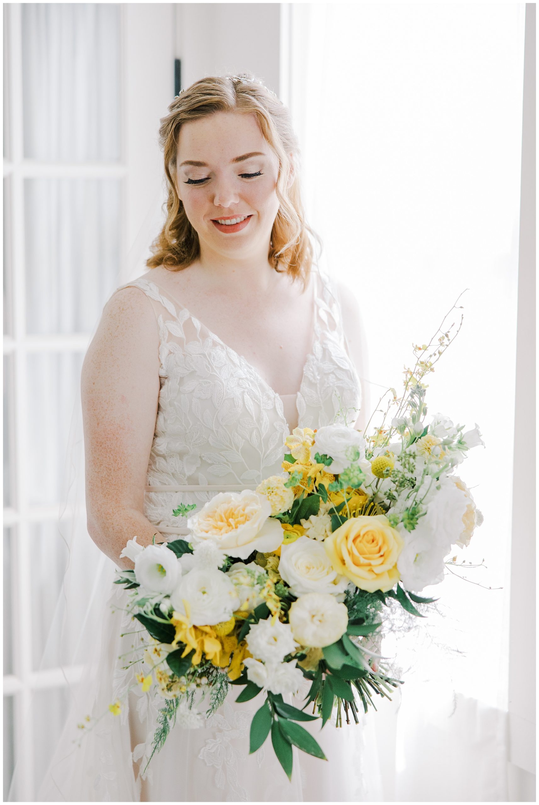 bride holding light airy wedding bouquet of white and yellow flowers