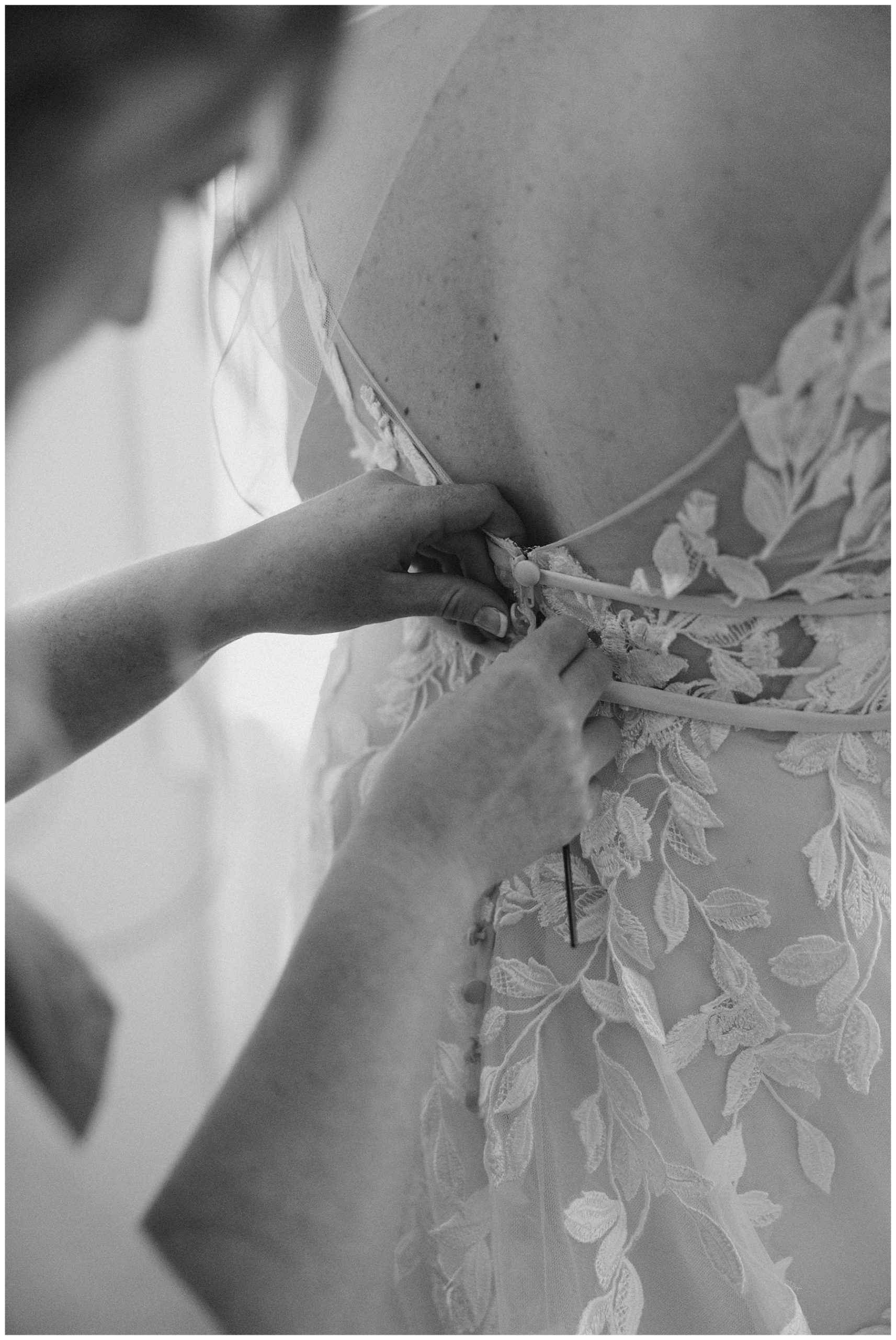 bride getting her dress buttoned 