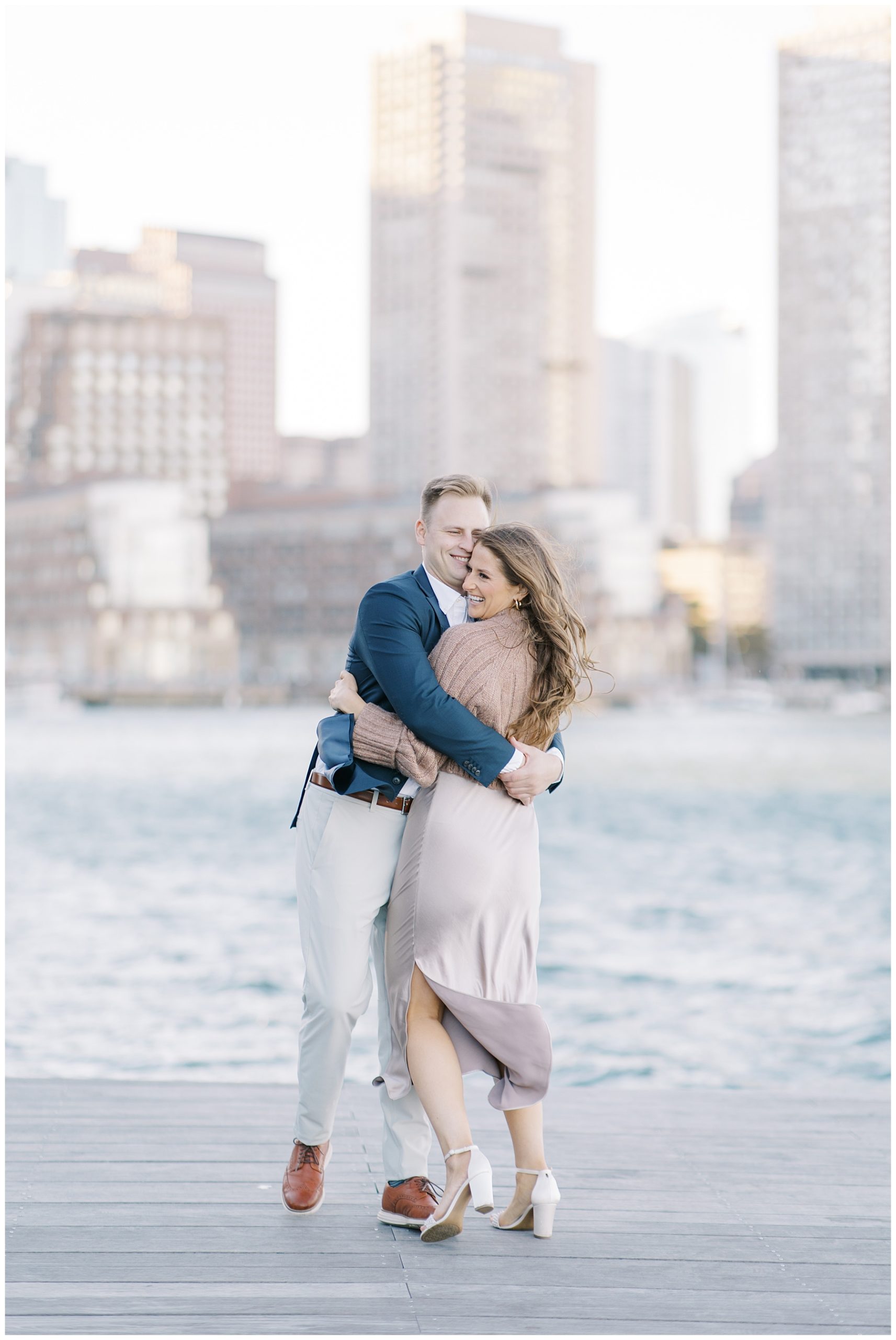 couple walk along the boardwalk at Fan Pier Park during Romantic Boston Engagement