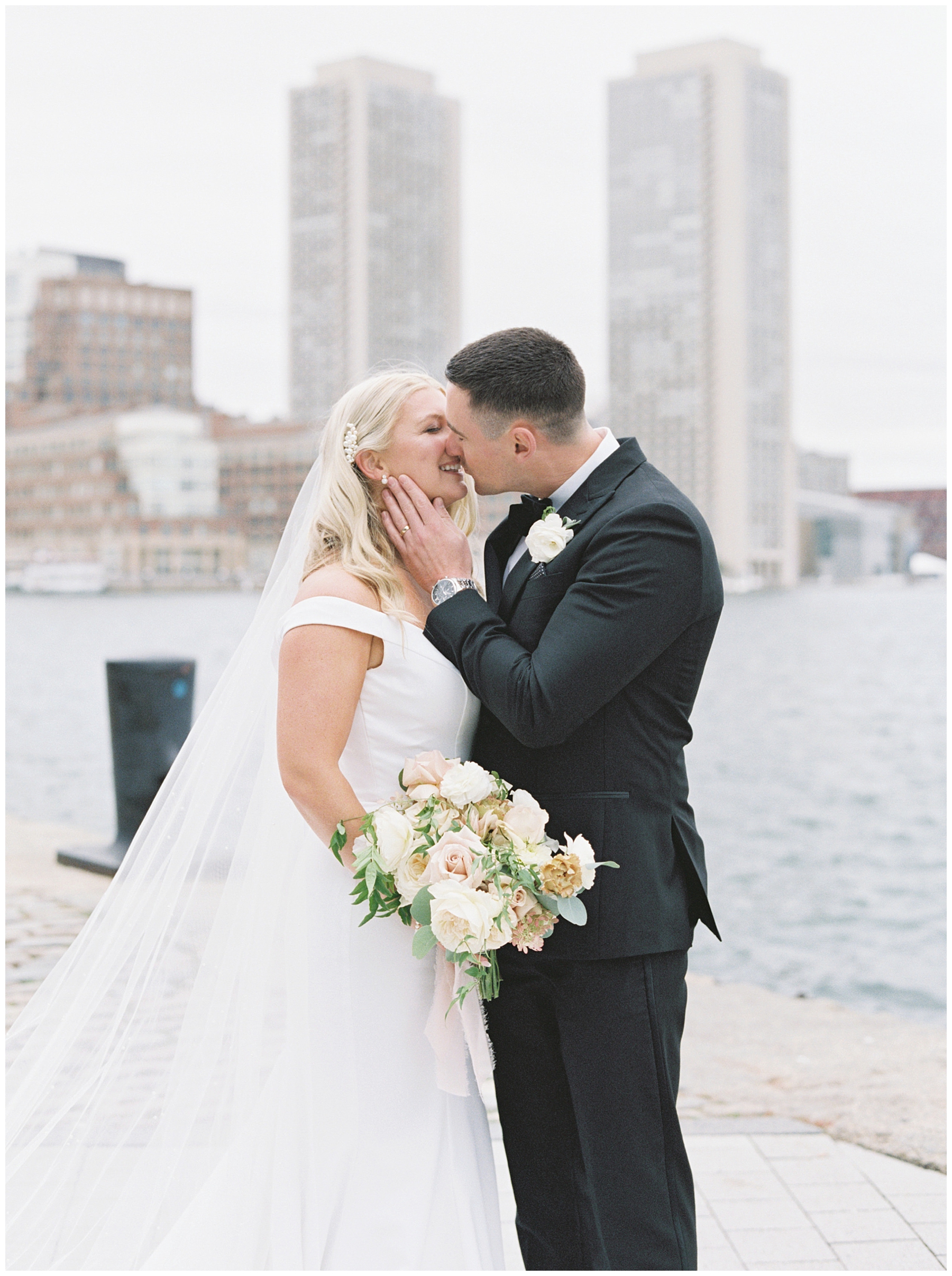 newlyweds kiss with Boston skyline in the background