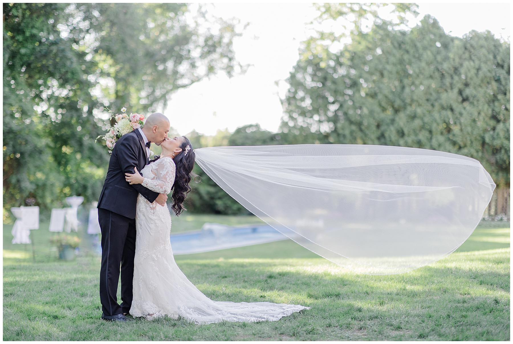 couple kiss as wedding veil floats behind them 