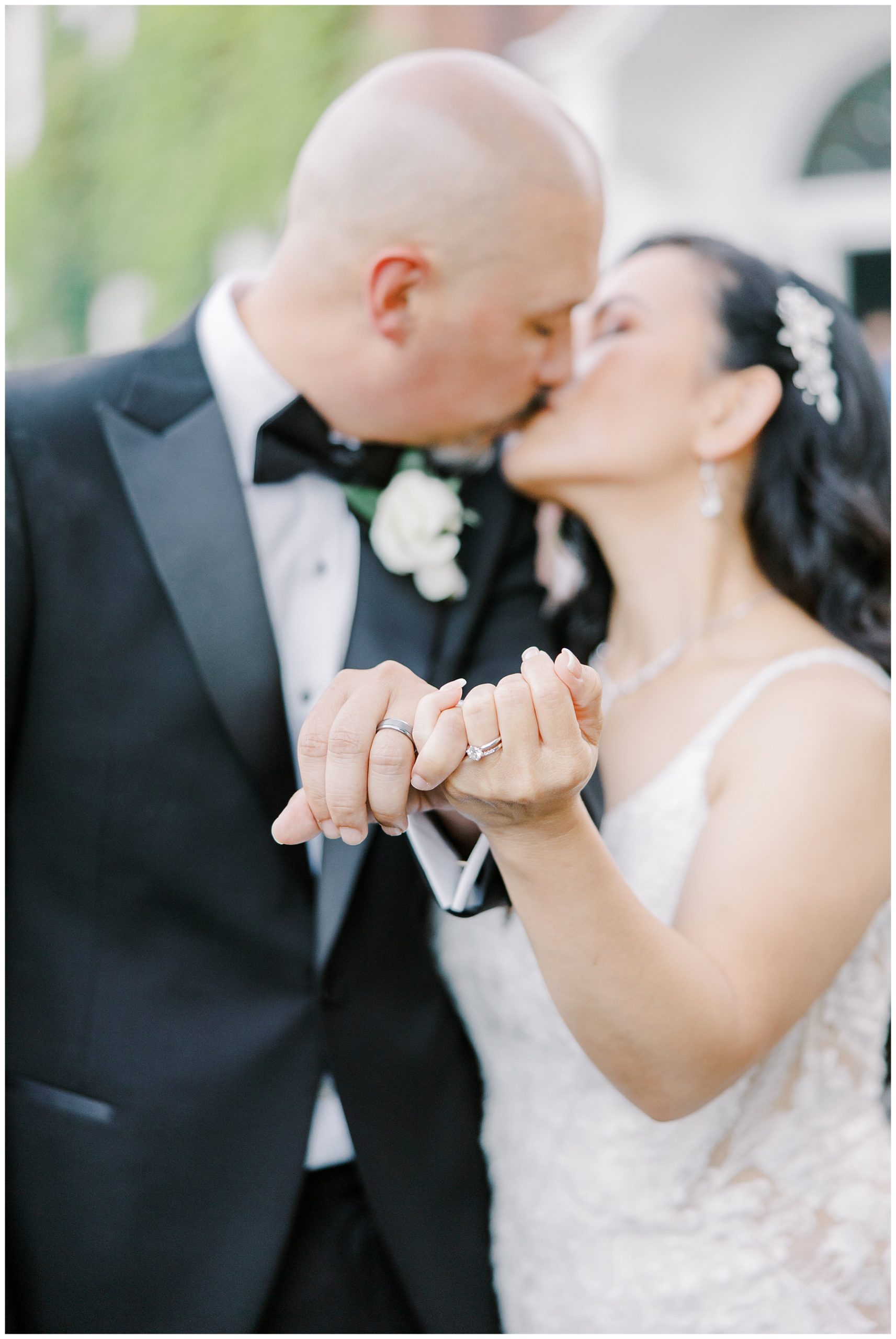 couple kiss and show off wedding rings 
