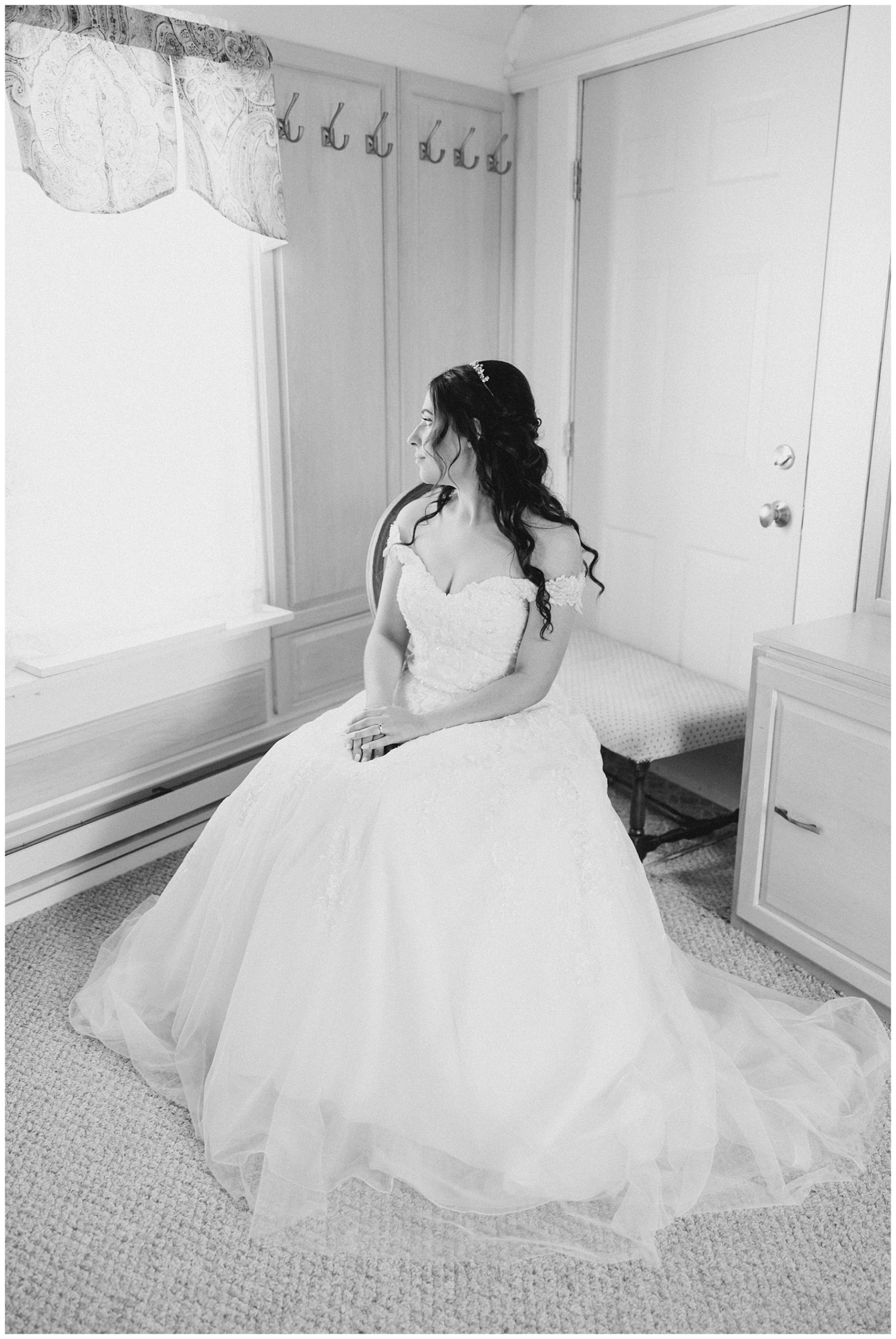 bride sits in wedding dress looking out window