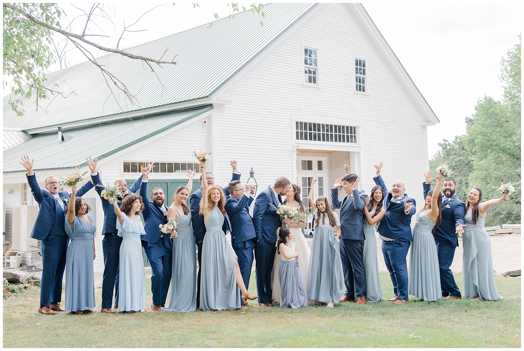 wedding party in shades of blue celebrate as newlyweds kiss