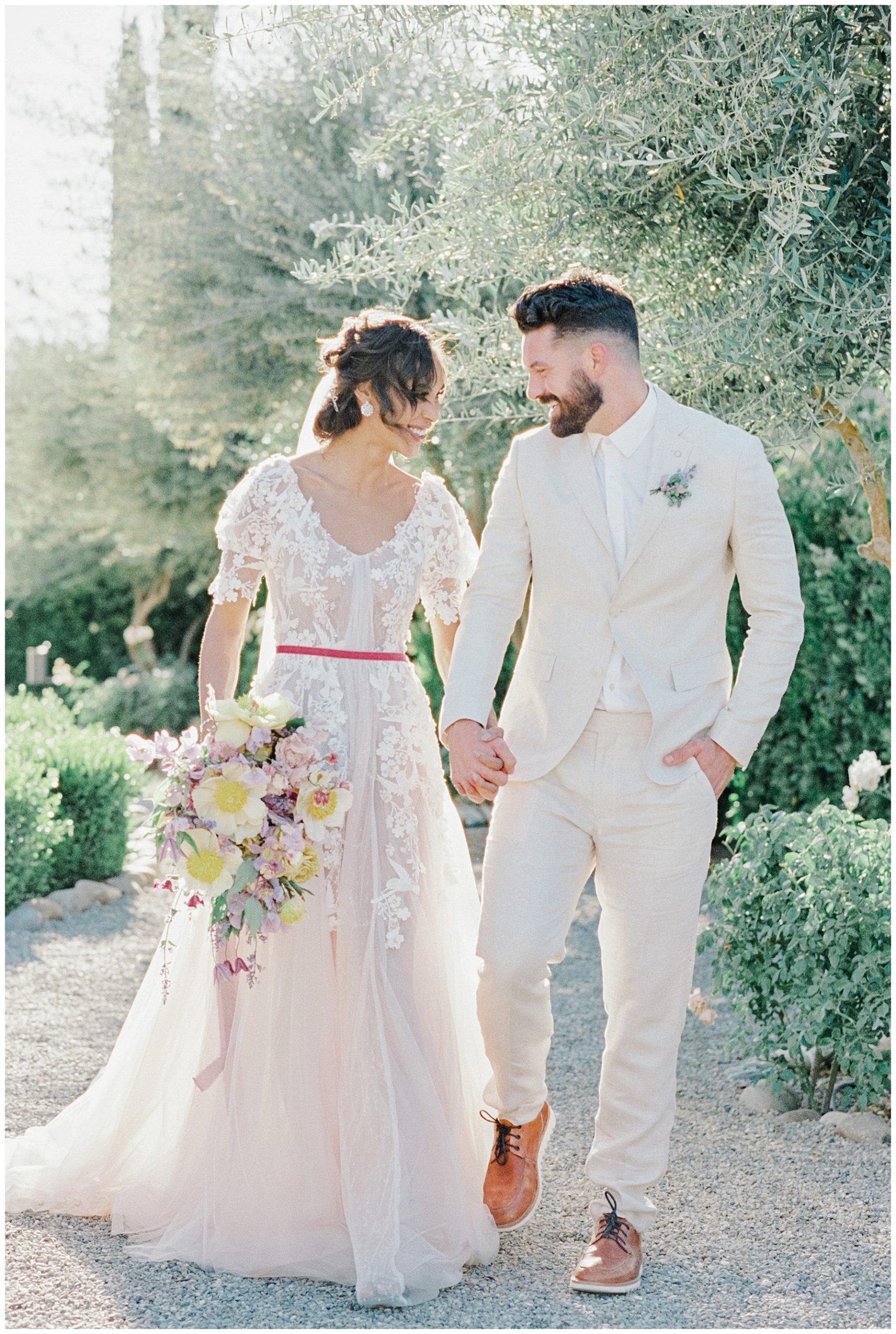 newlyweds walk hand in hand through vineyard in Paso Robles, CA