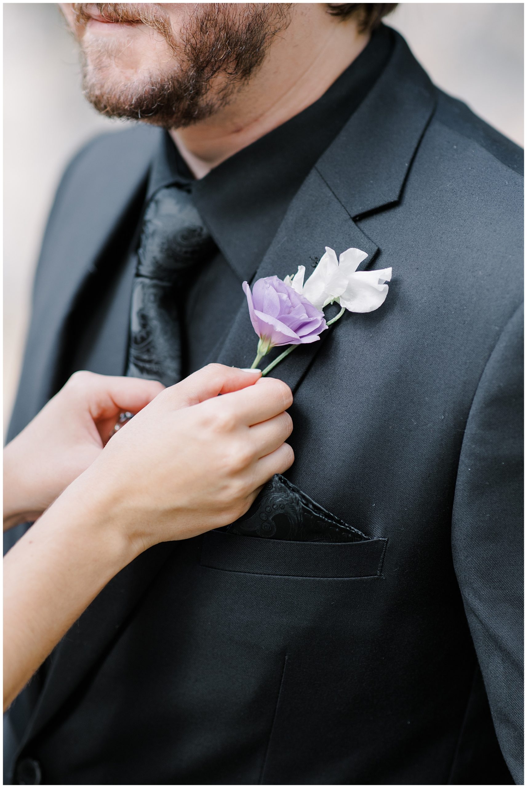 bride helps groom with boutonniere 