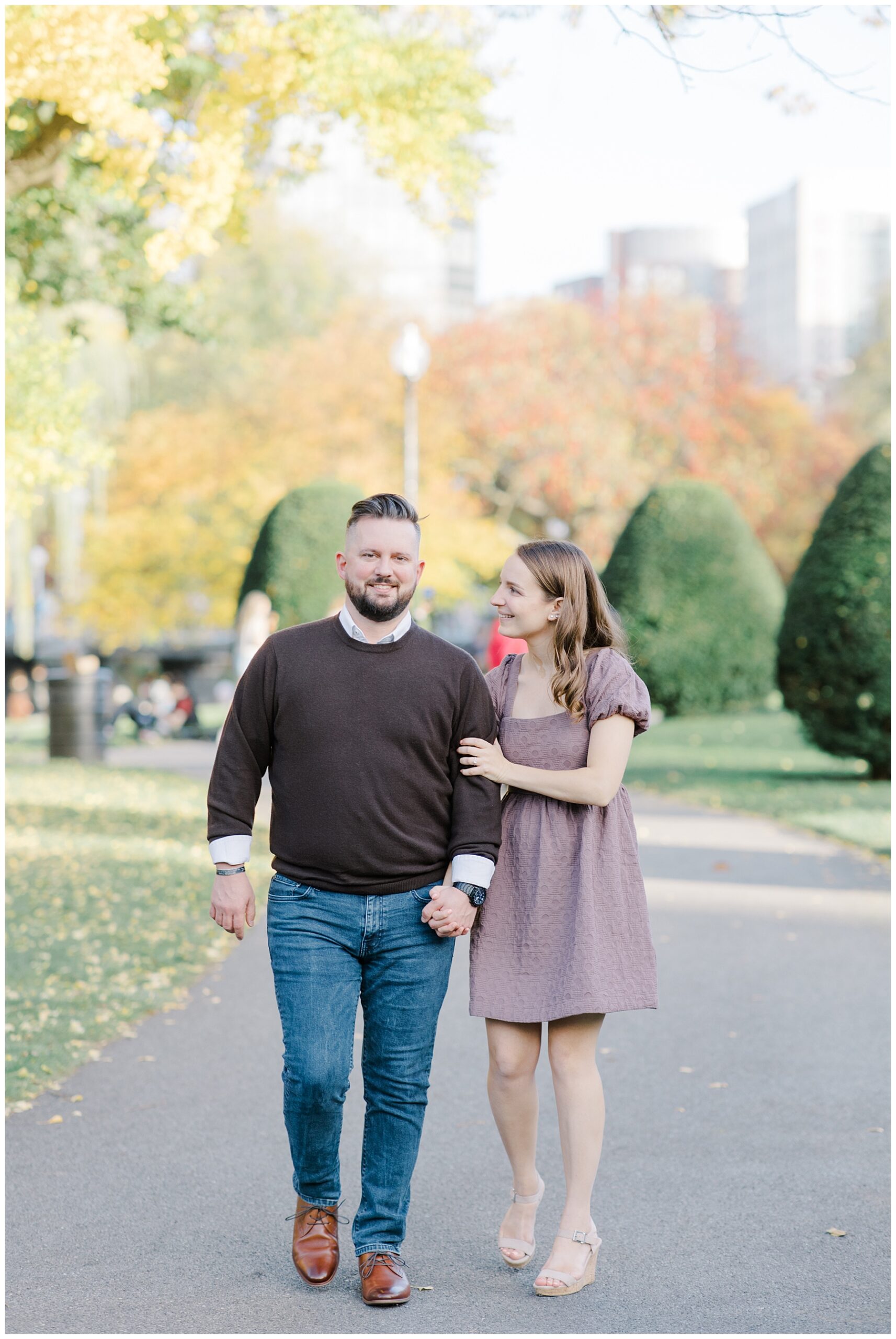 couple walk in Boston park during fall engagement session