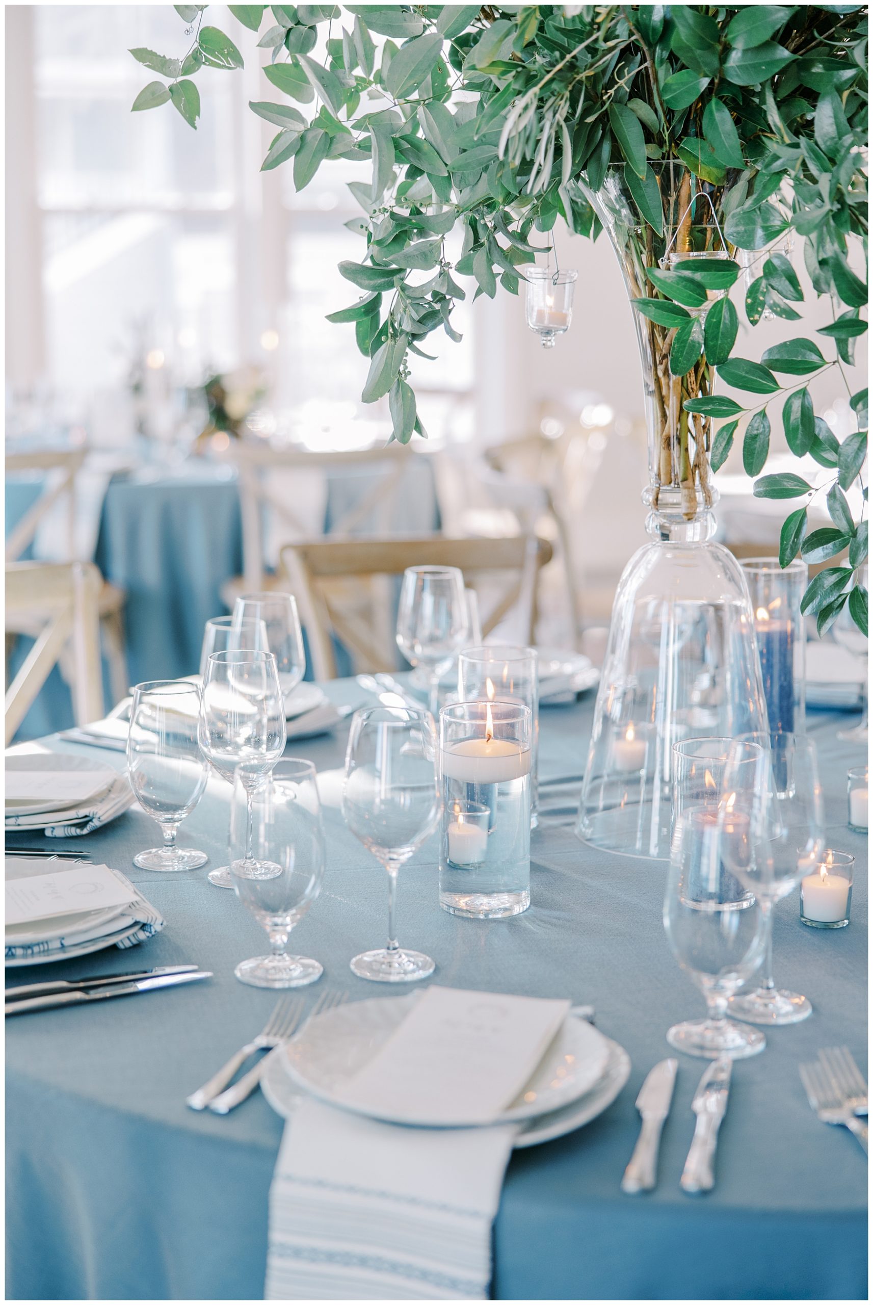 blue tablecloths and centerpieces of greenery at coastal wedding 