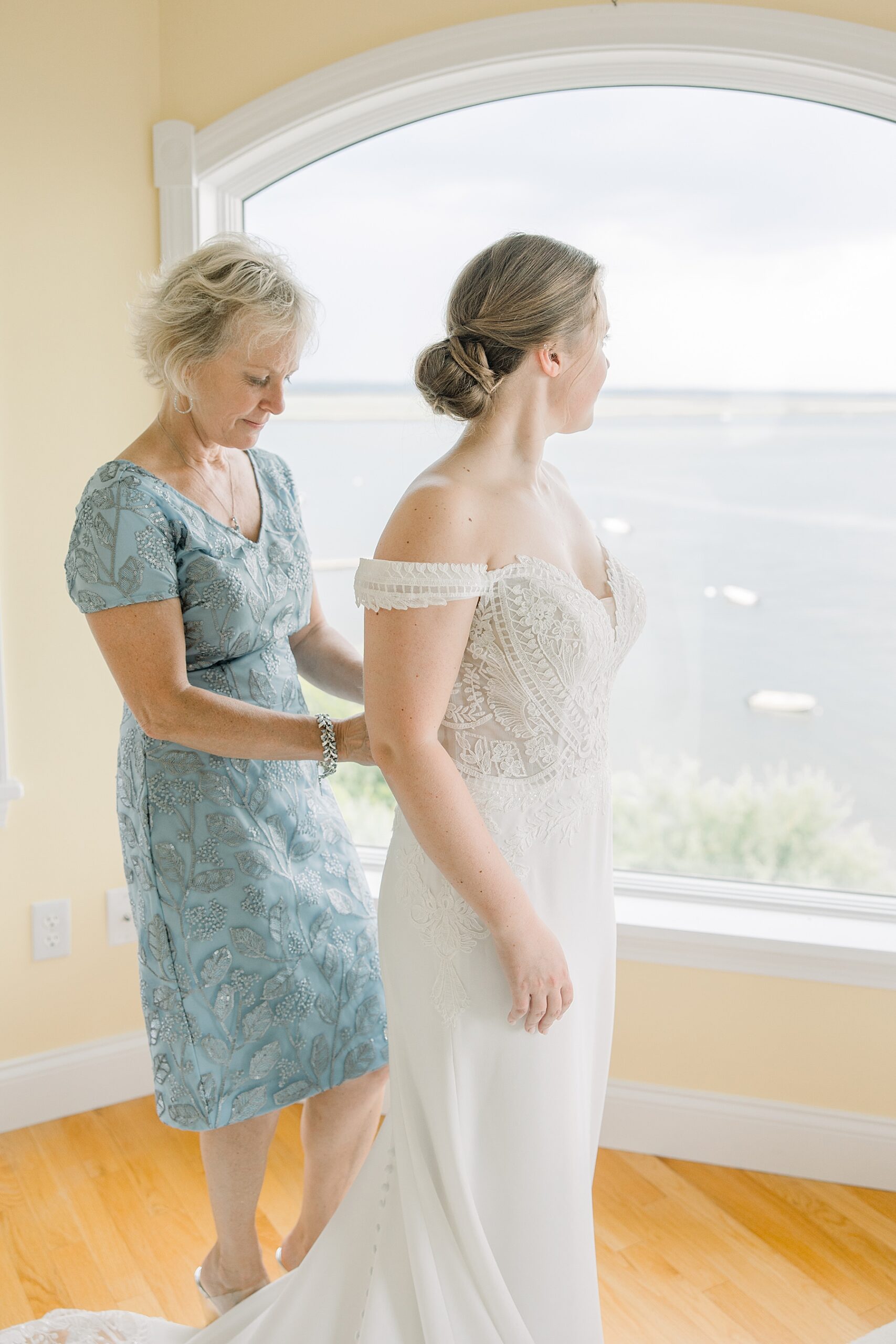 mom helping bride into dress 