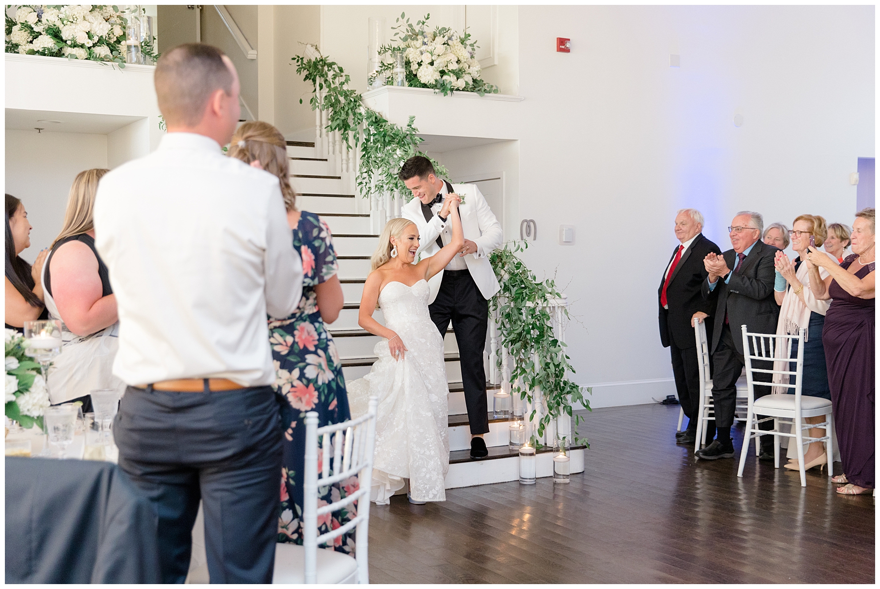 bride and groom enter reception down white staircase