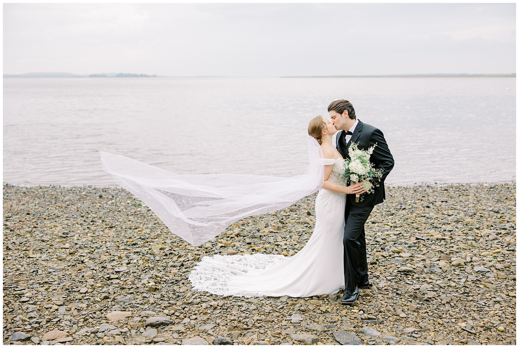 Romantic wedding portraits of bride and groom kissin on the bay 