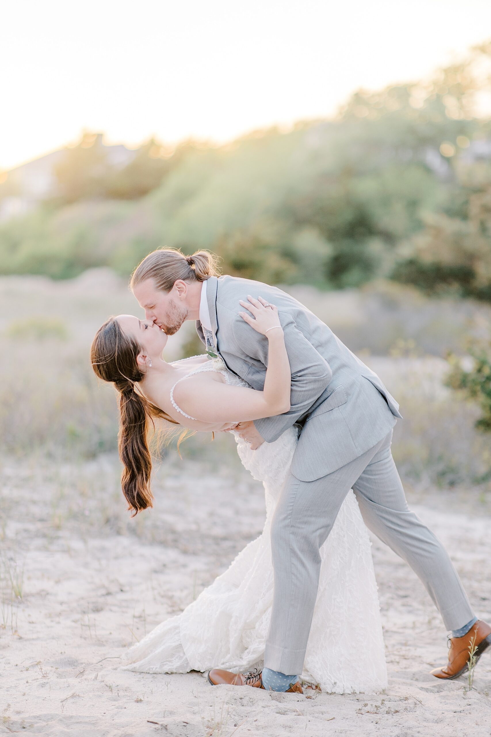 groom kisses his bride and dips her in his arms during sunset portraits 
