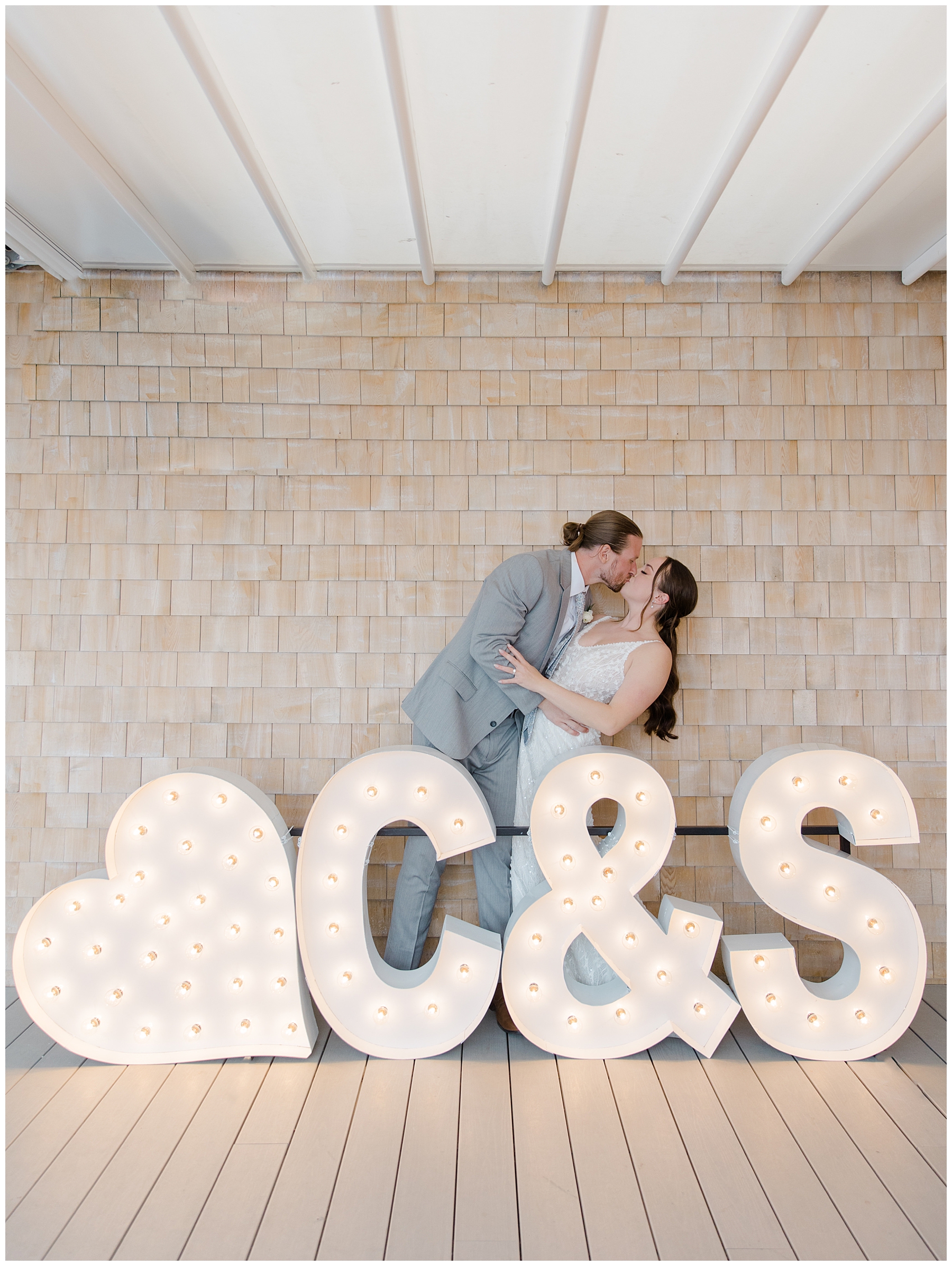 newlyweds kiss by light up sign with initials 