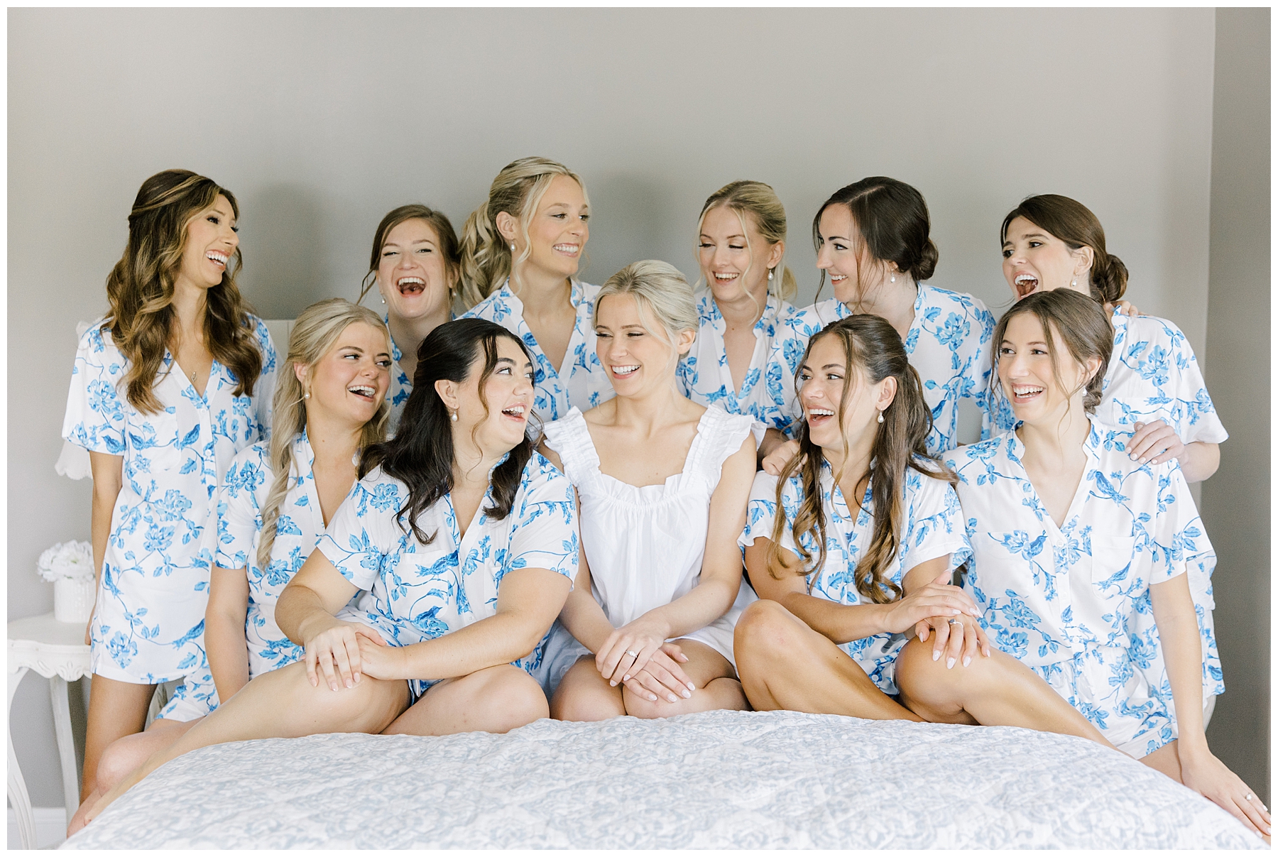 bride and bridesmaids sit on bed the morning of wedding